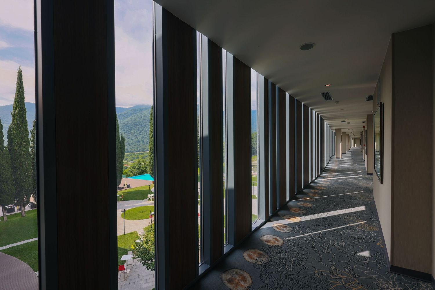 Long corridor with floor-to-ceiling windows offering panoramic mountain views.
