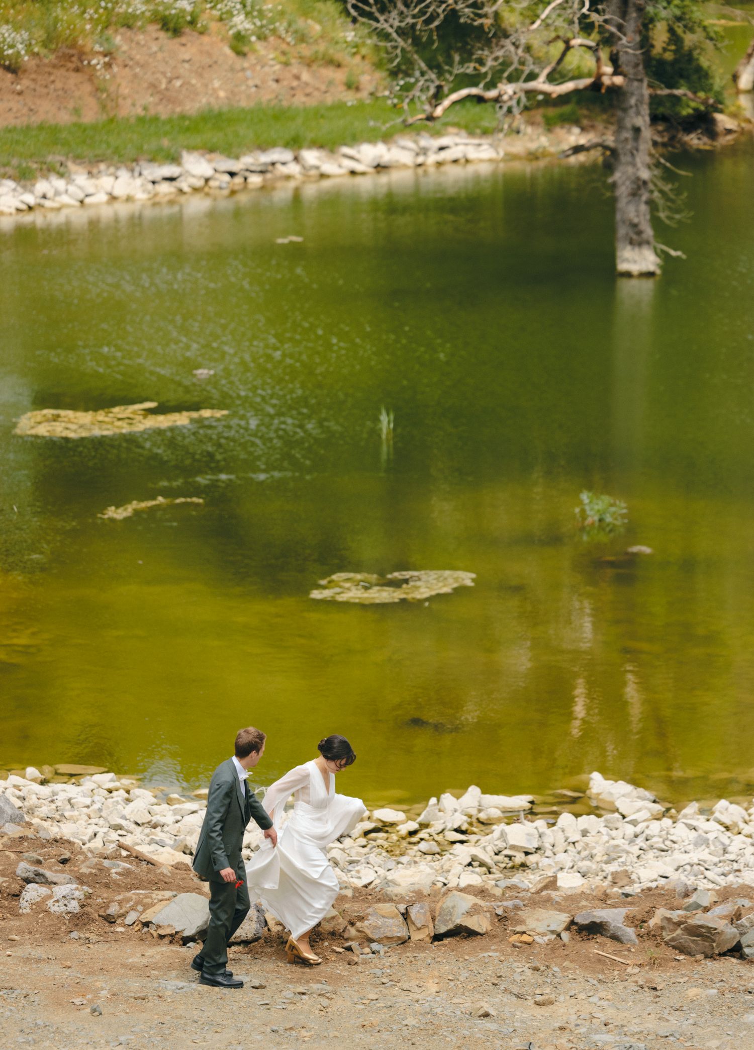 Scenic lakeside setting with green water, rocky shore, and surrounding forest landscape.