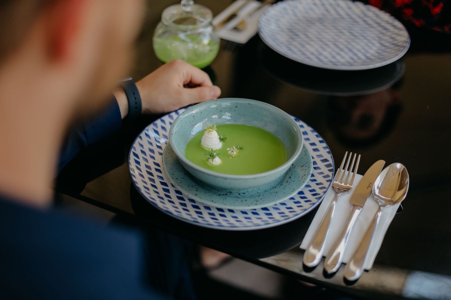 Modern fine dining presentation with green soup and elegant place settings.