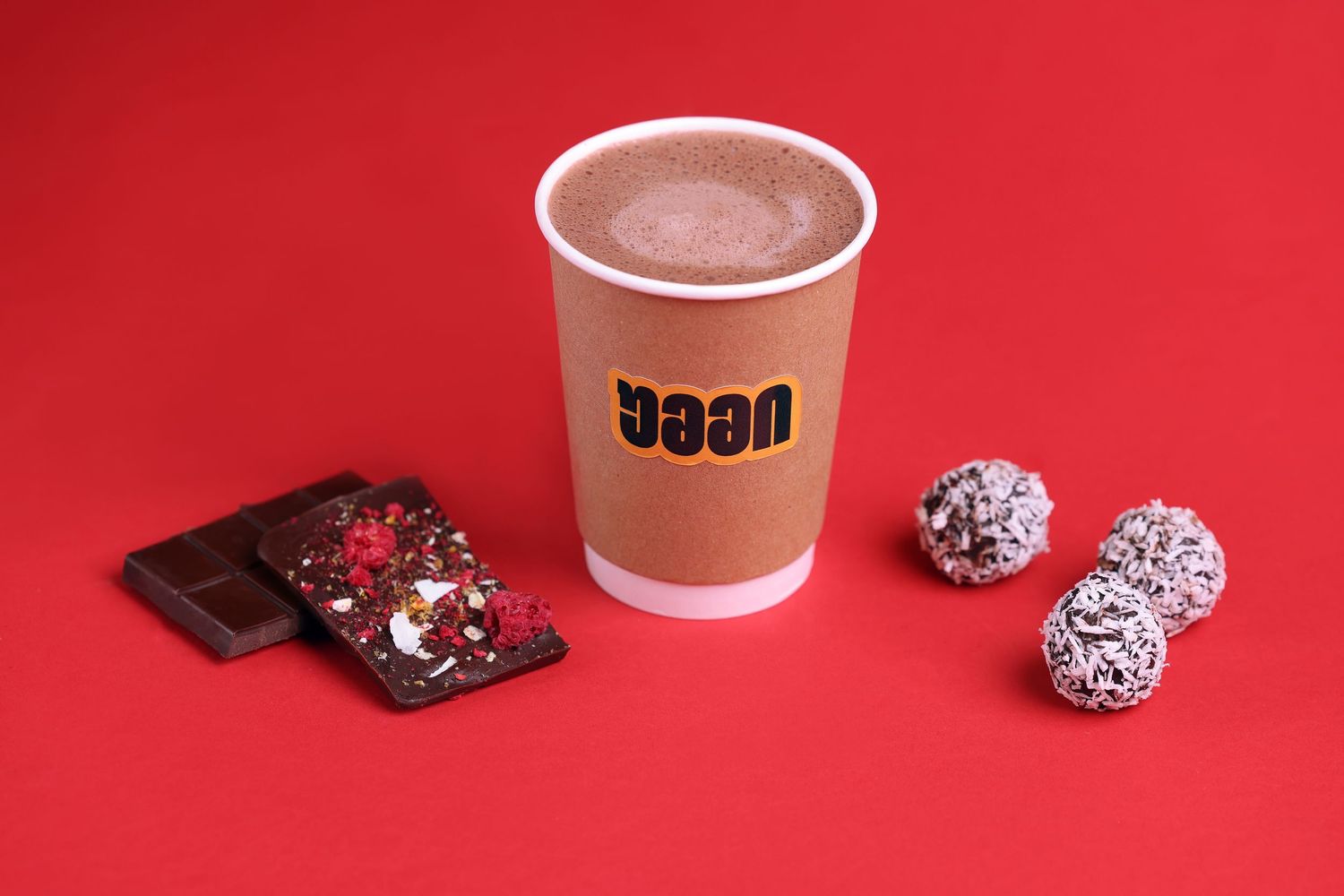 Hot chocolate drinks and chocolate truffles arranged on red background.