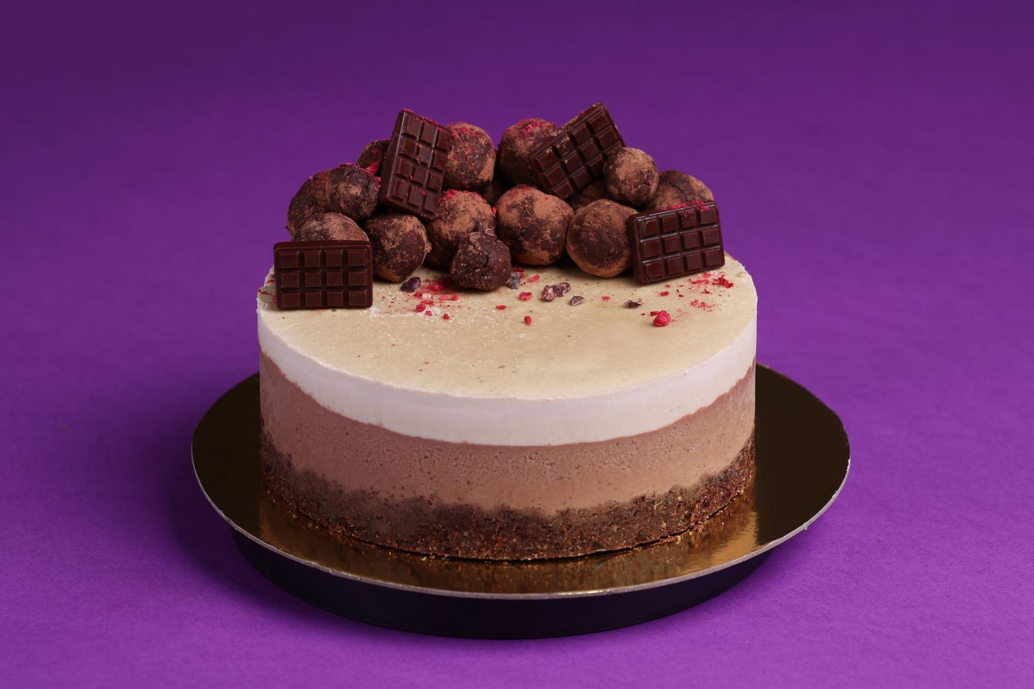 Sequence showing layered chocolate cake with truffles and garnish on purple background.