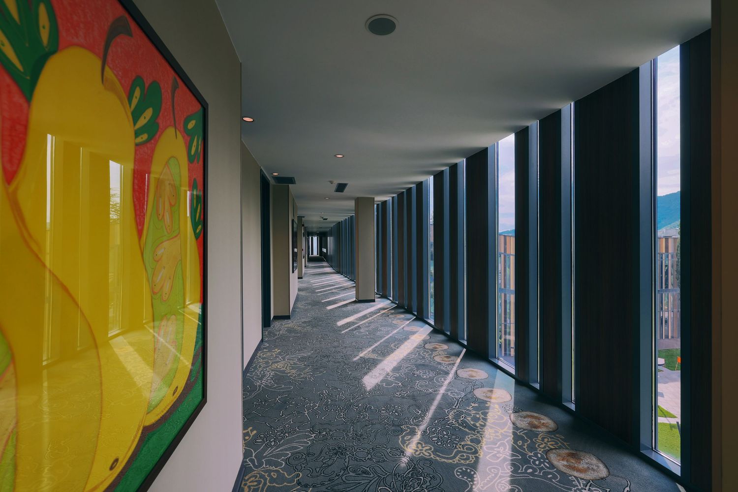 Hallway with colorful abstract wall murals and natural lighting from windows.