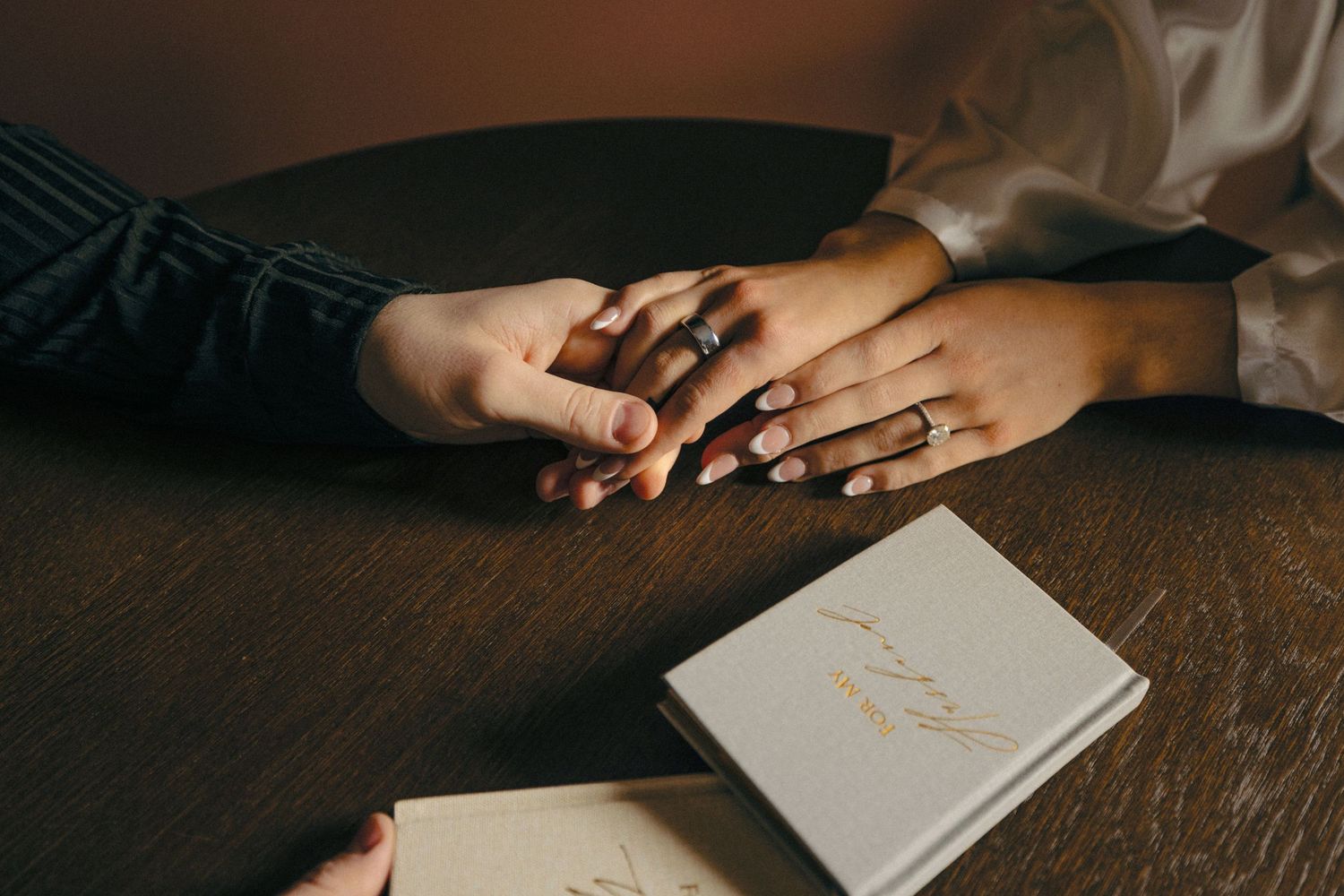 White notebook or journal rests on dark wooden table surface in moody lighting.