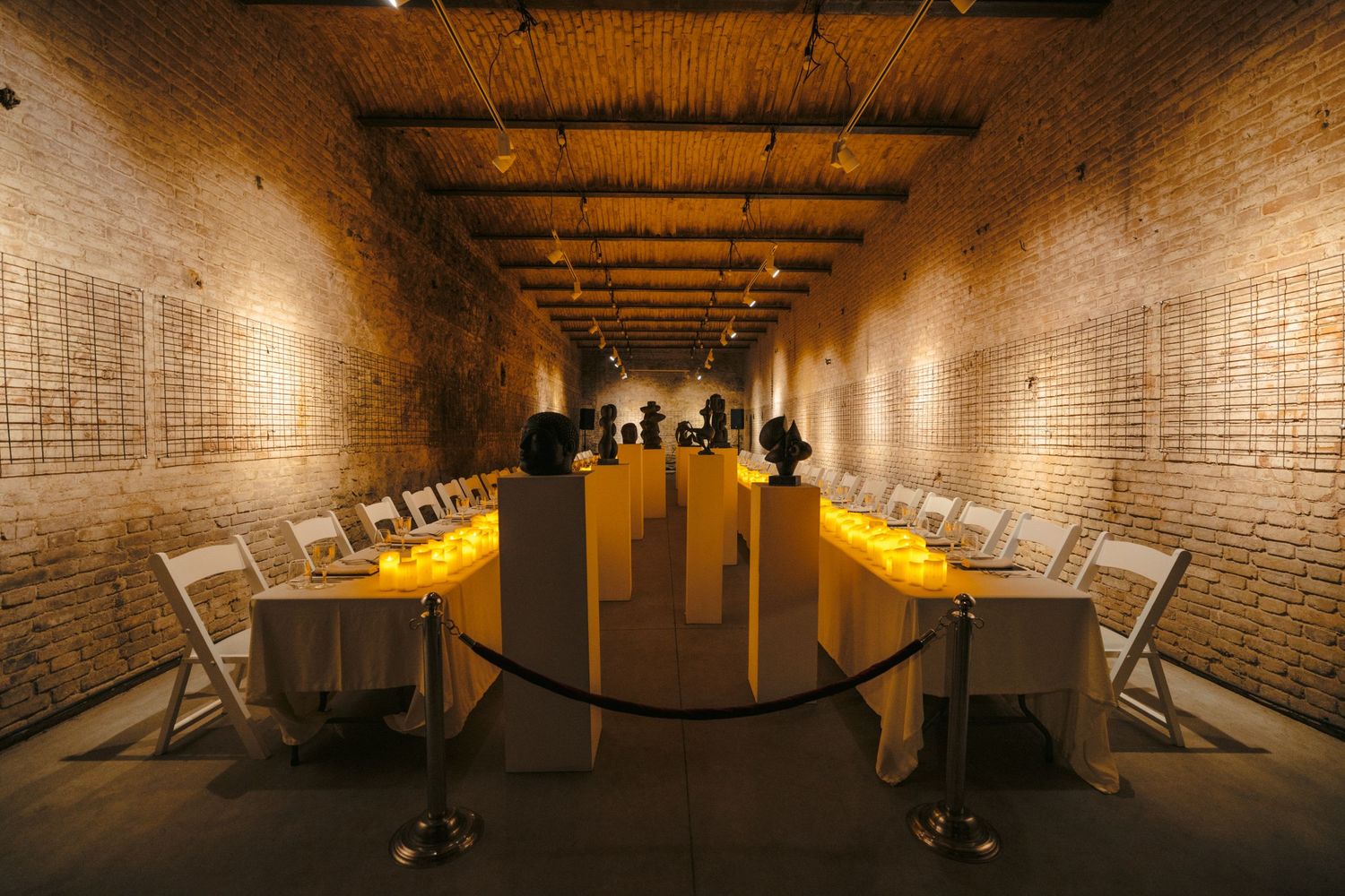 Panoramic view of a brick-lined tunnel gallery with warm lighting and art displays.