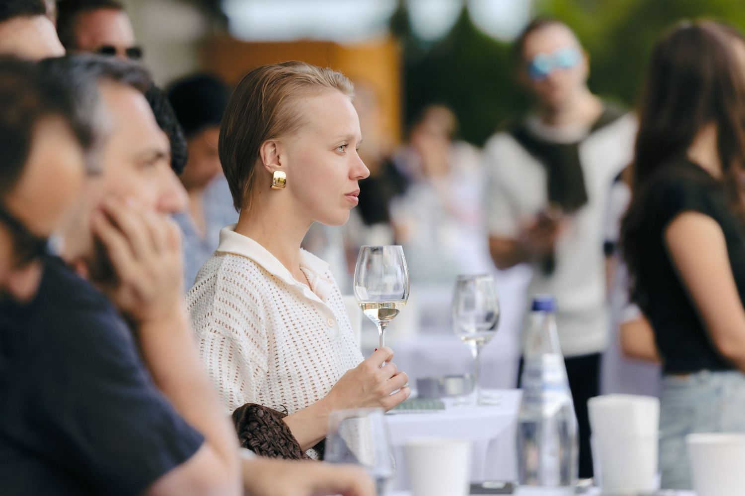 People seated at tables during an outdoor social gathering.