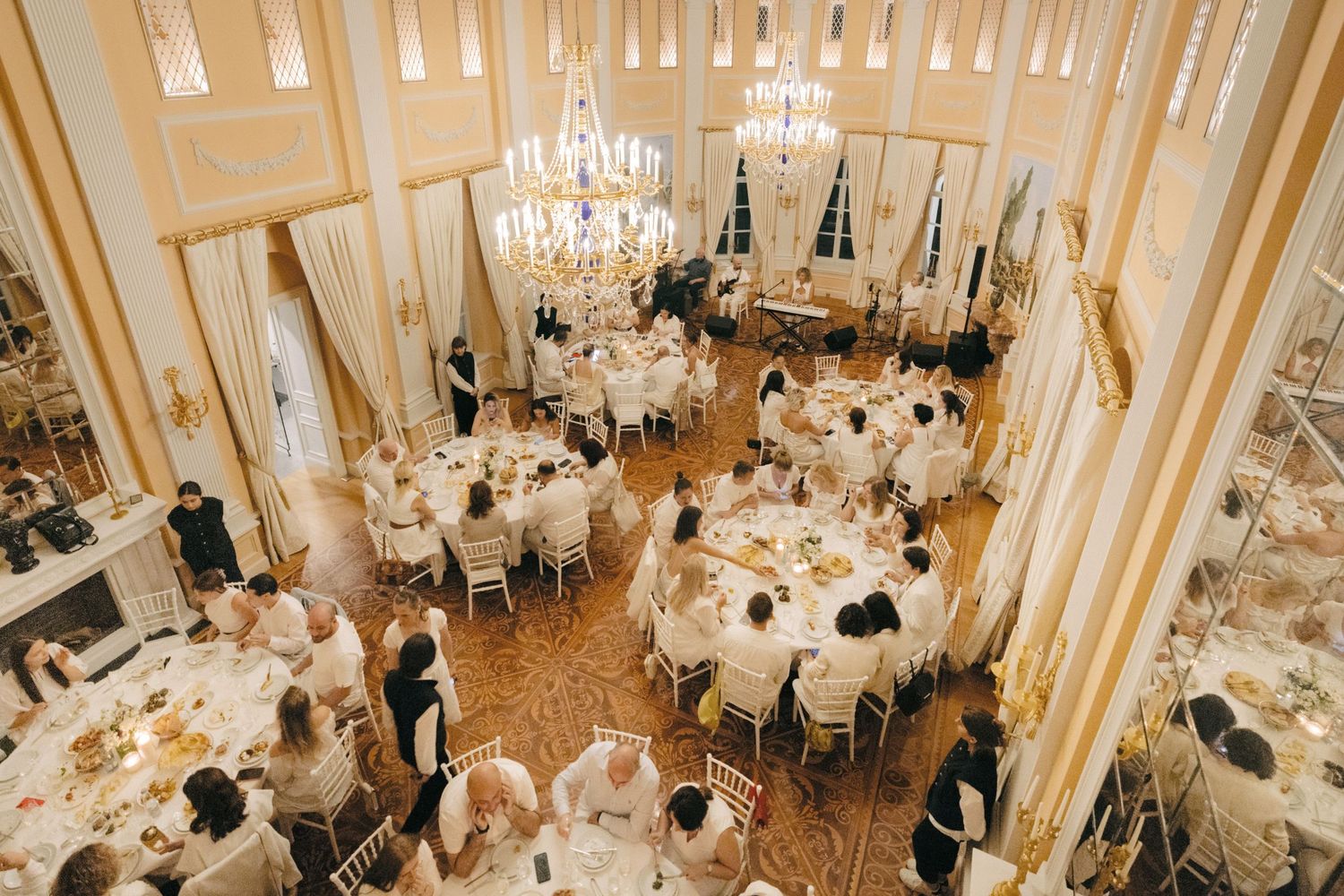 Overhead view of an elegant ballroom with crystal chandeliers and round dining tables.