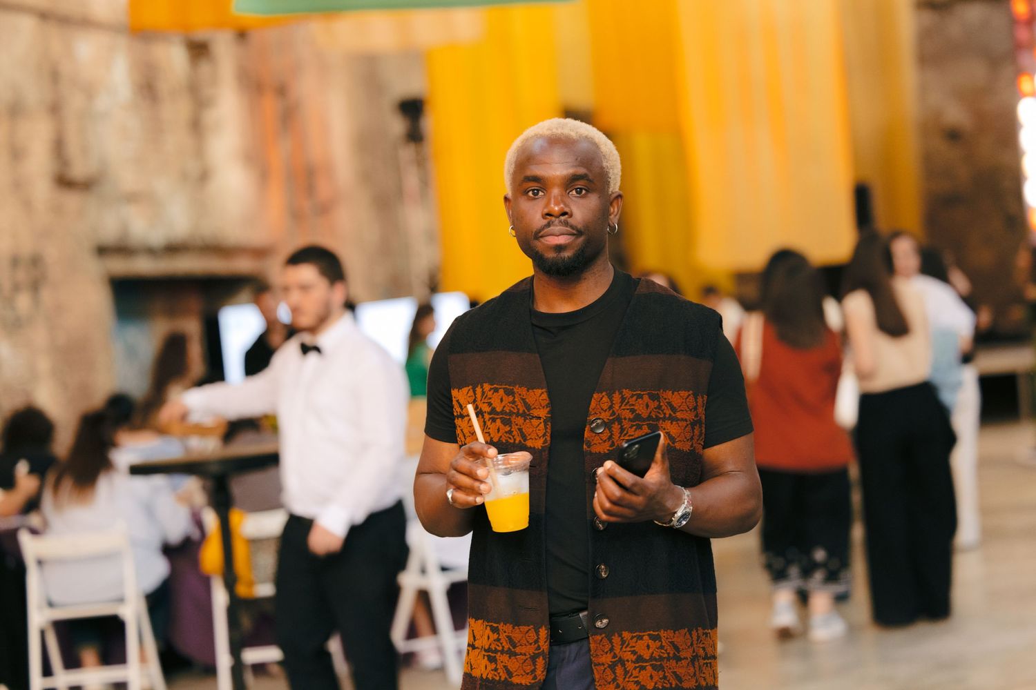 Guests enjoying drinks and conversation at an indoor event with warm lighting.