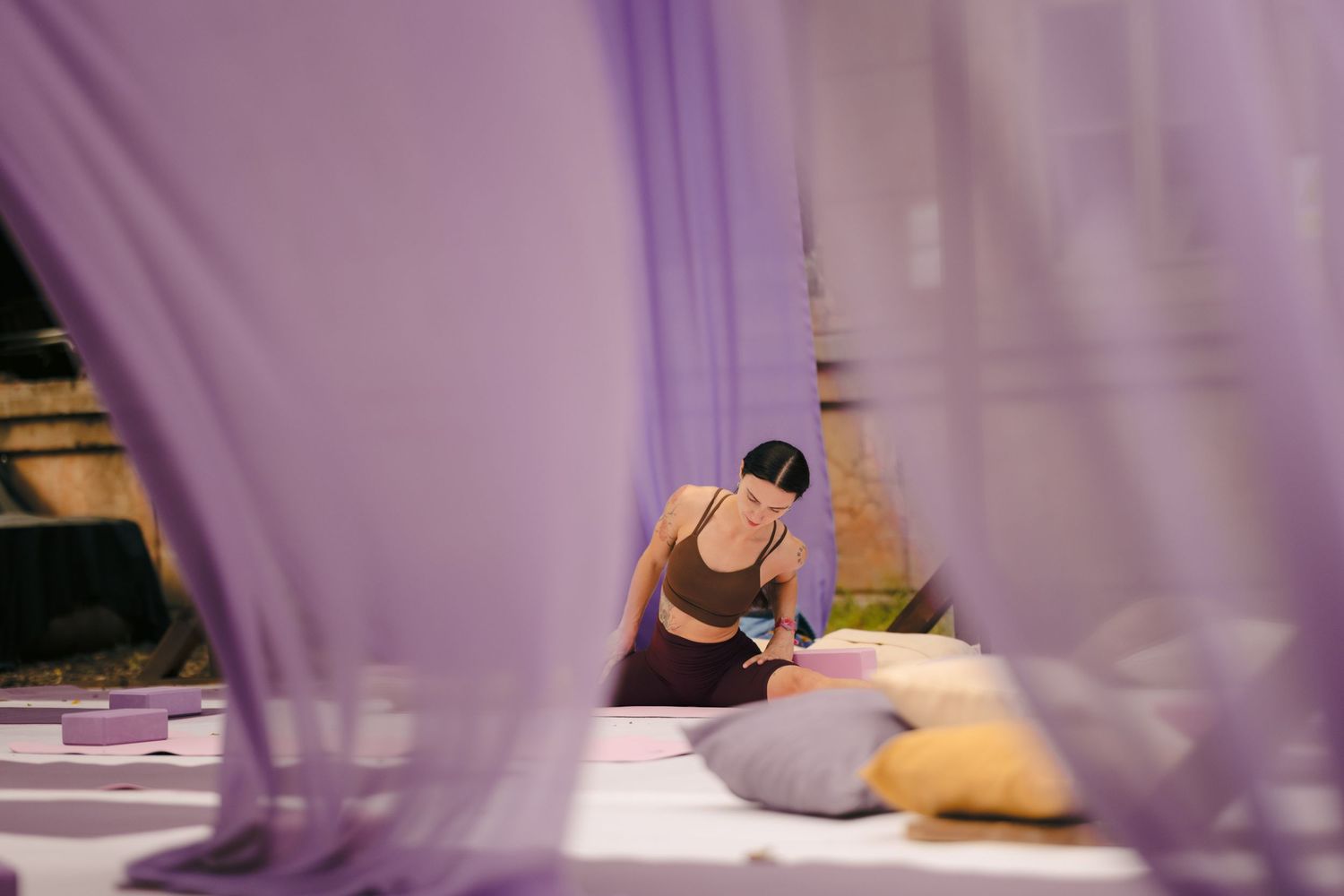 Purple and yellow fabric drapes create an artistic ambiance in an indoor venue space.