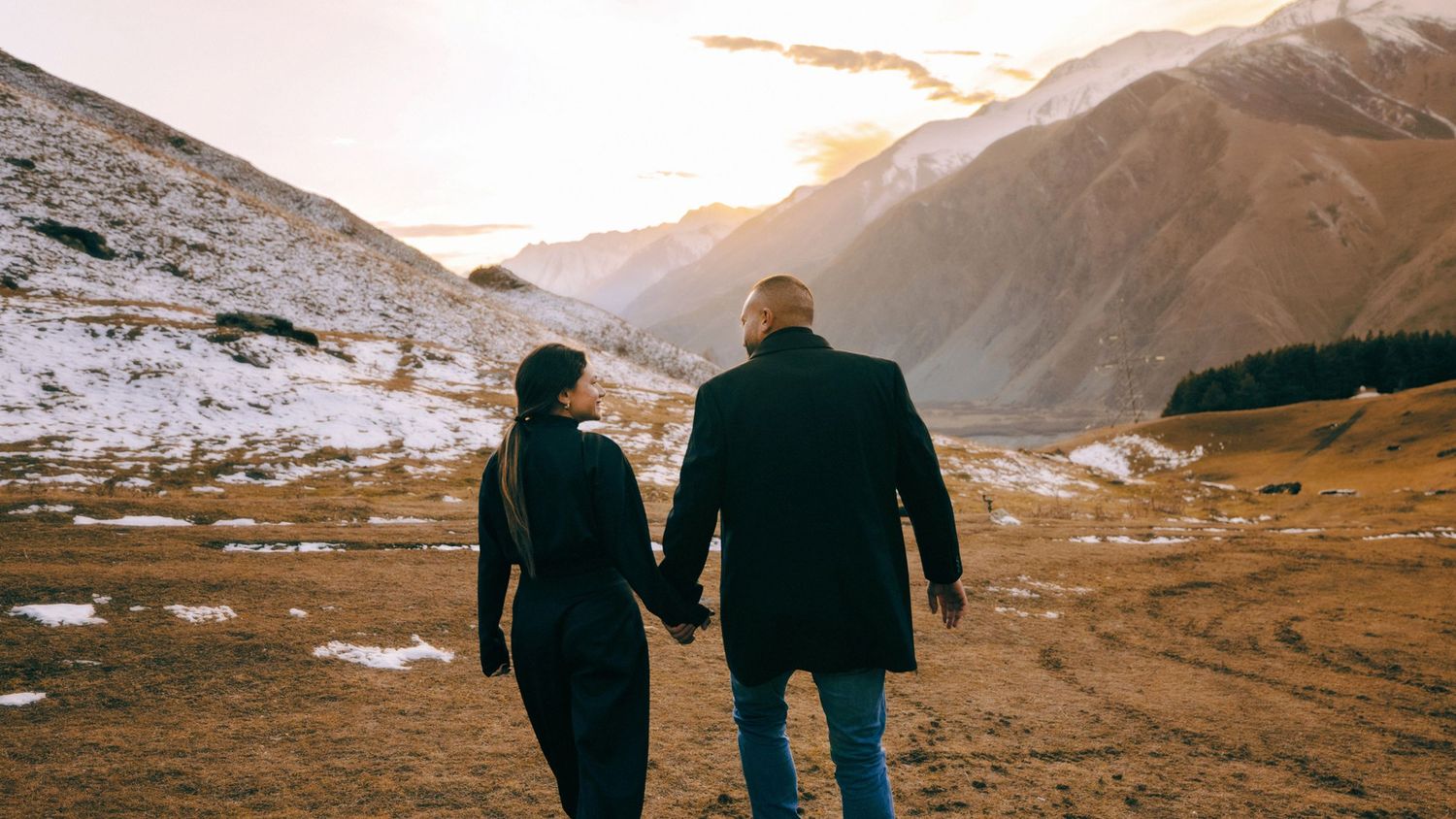 Silhouettes of people walking along a mountain ridge during sunset.