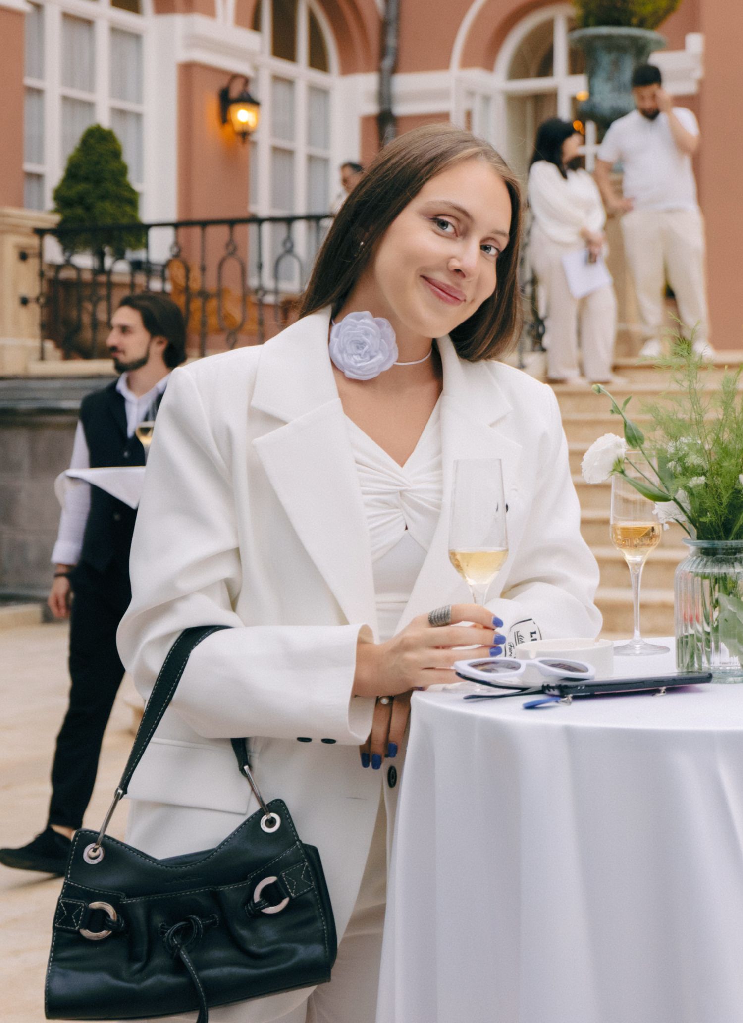 Guests seated at white-clothed tables during an elegant outdoor social event.