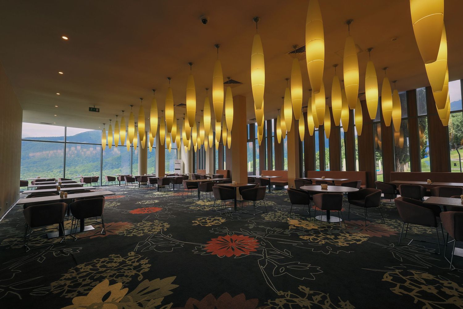 Restaurant dining area with rows of glowing yellow pendant lamps overhead.