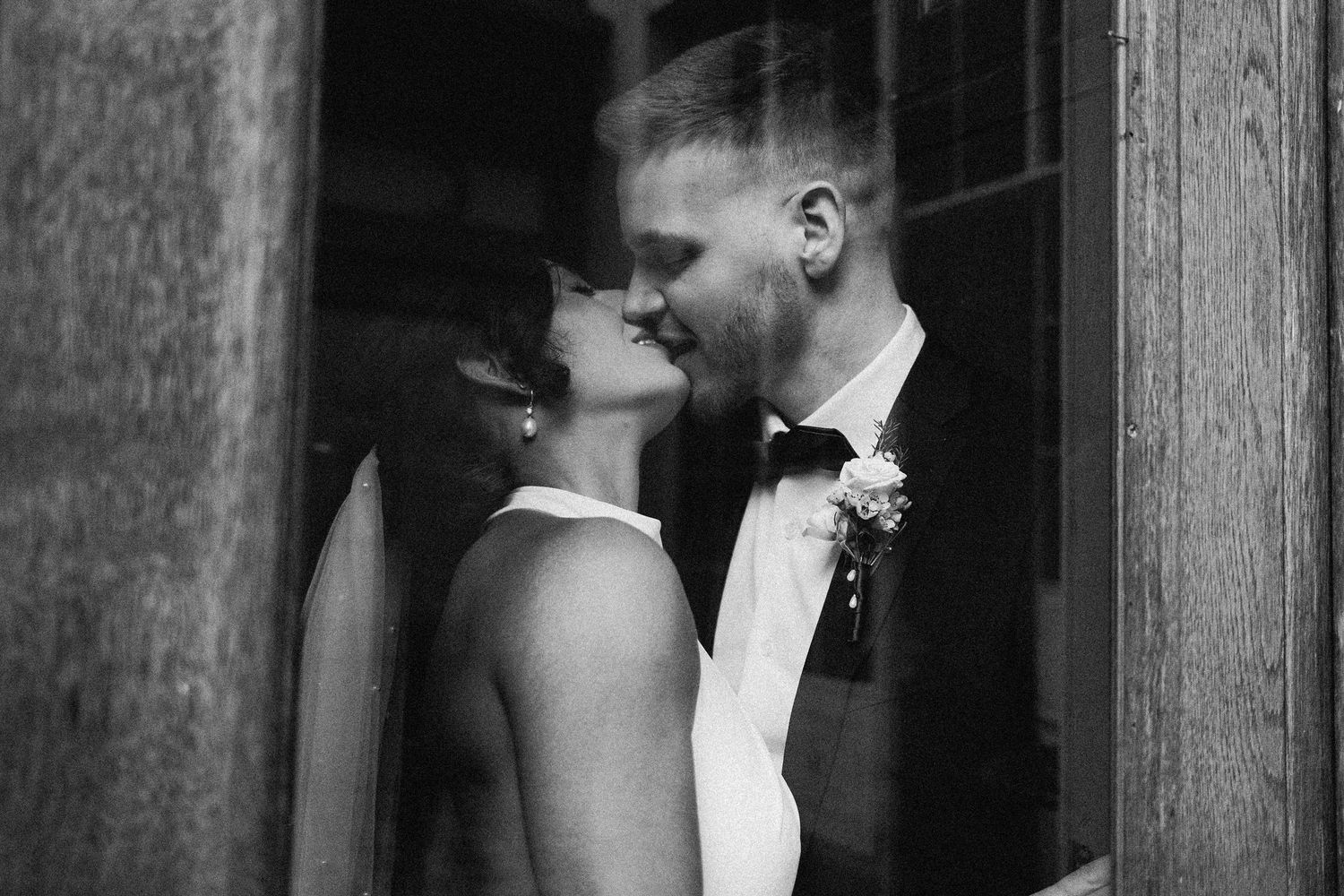 Black and white romantic wedding portrait showing intimate moment in doorway.