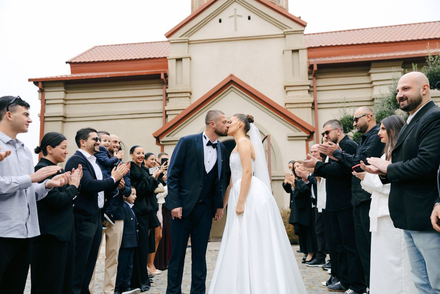 Wedding guests form a receiving line outside a church to celebrate the newlyweds.
