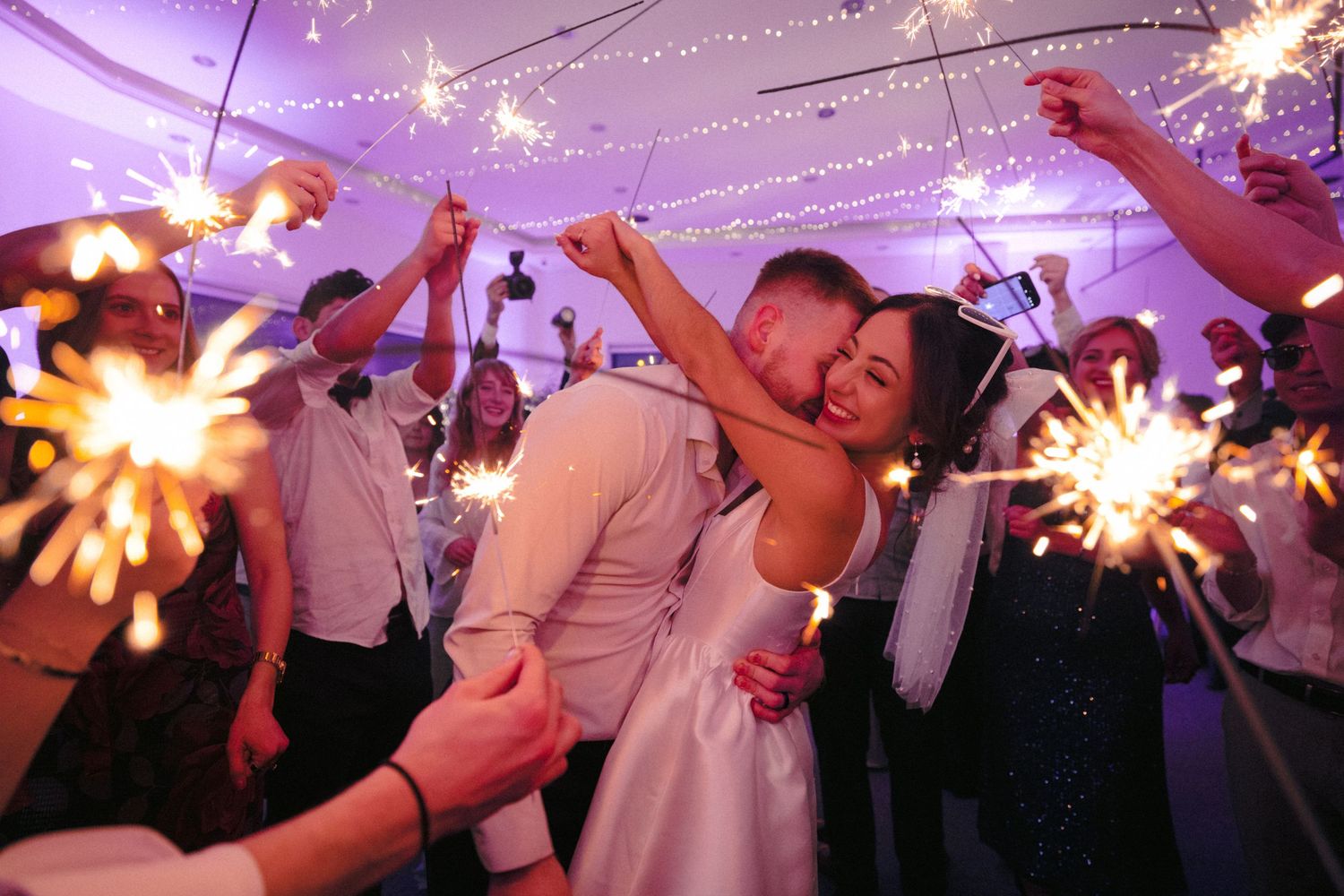 Wedding celebration with sparklers creating magical light trails as guests wave them in celebration.
