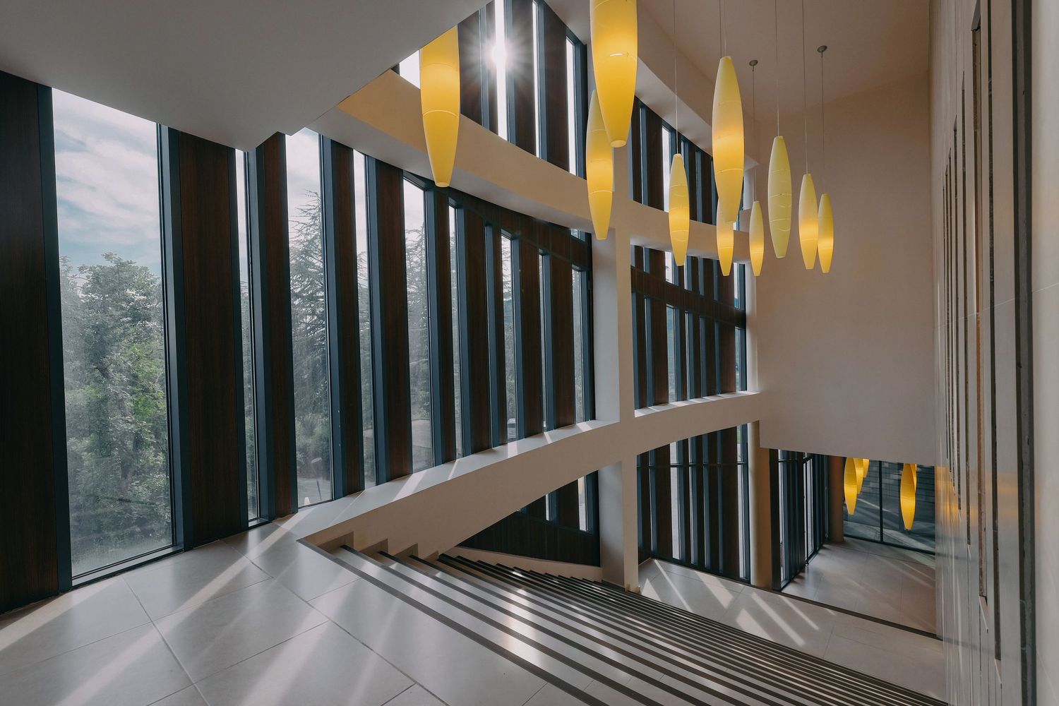Contemporary hallway featuring angular windows and suspended yellow lighting fixtures.