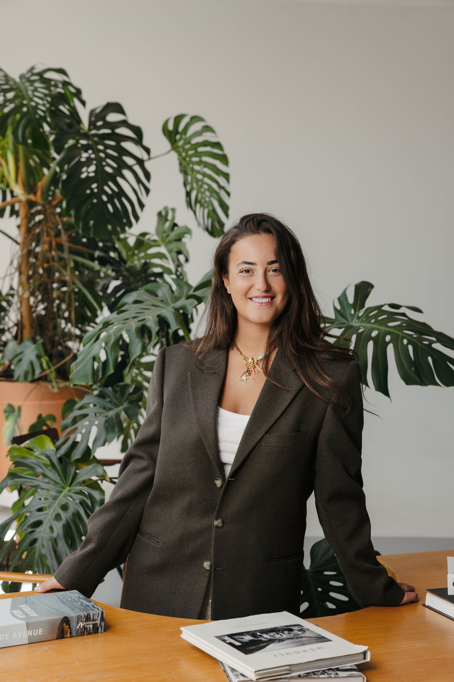 Professional headshots in office setting with monstera plants and wooden desk.