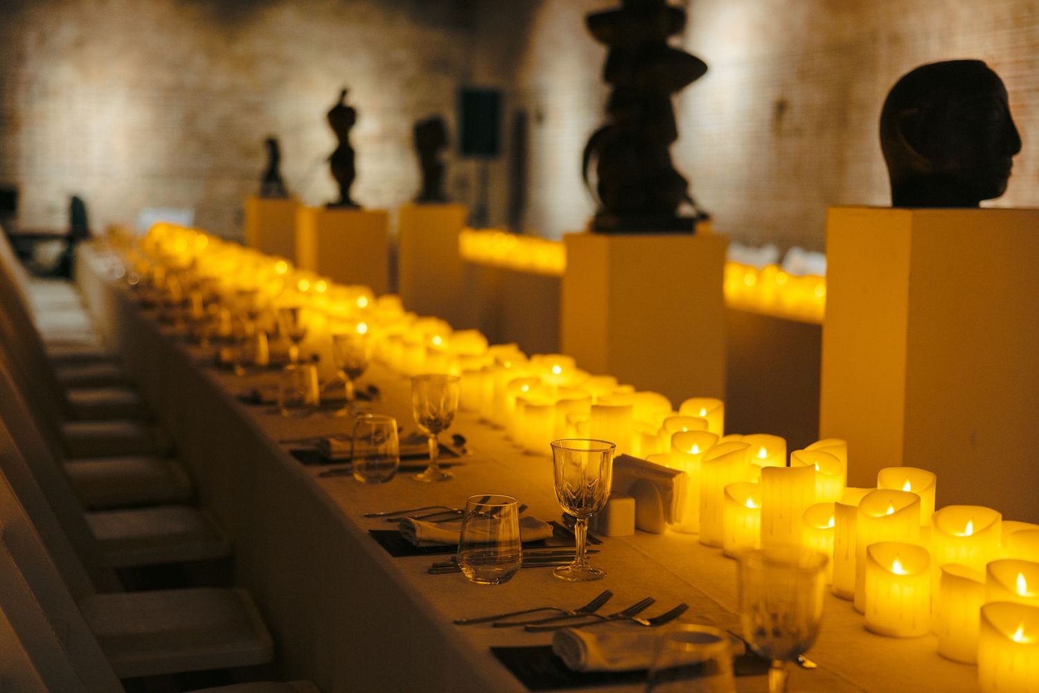 Long dining table set with glowing candles creating intimate atmosphere.