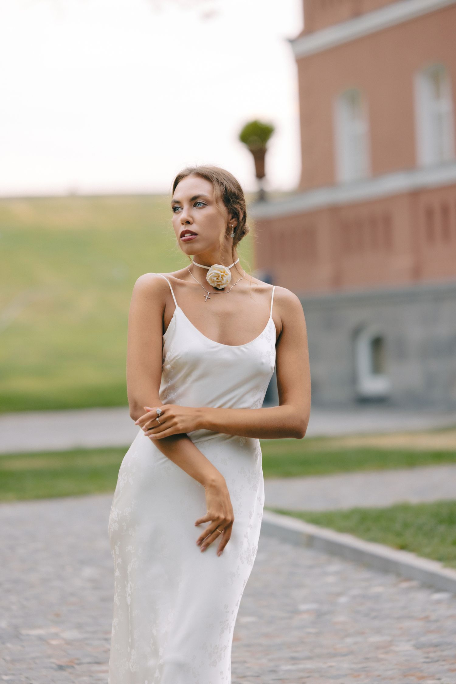 Dancer in white dress performing graceful movements on cobblestone path.