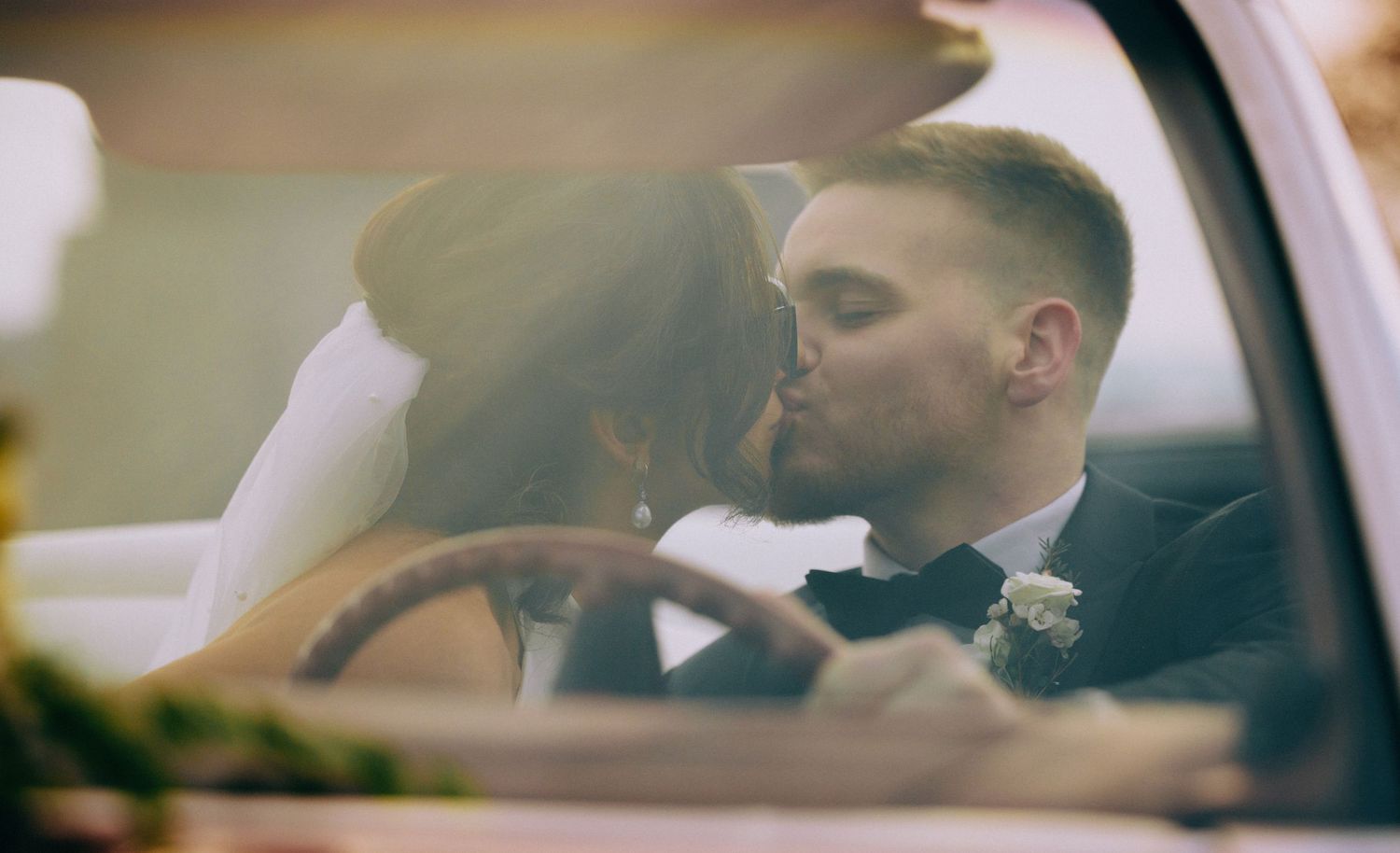 Interior view of a classic car with passengers during a wedding celebration.