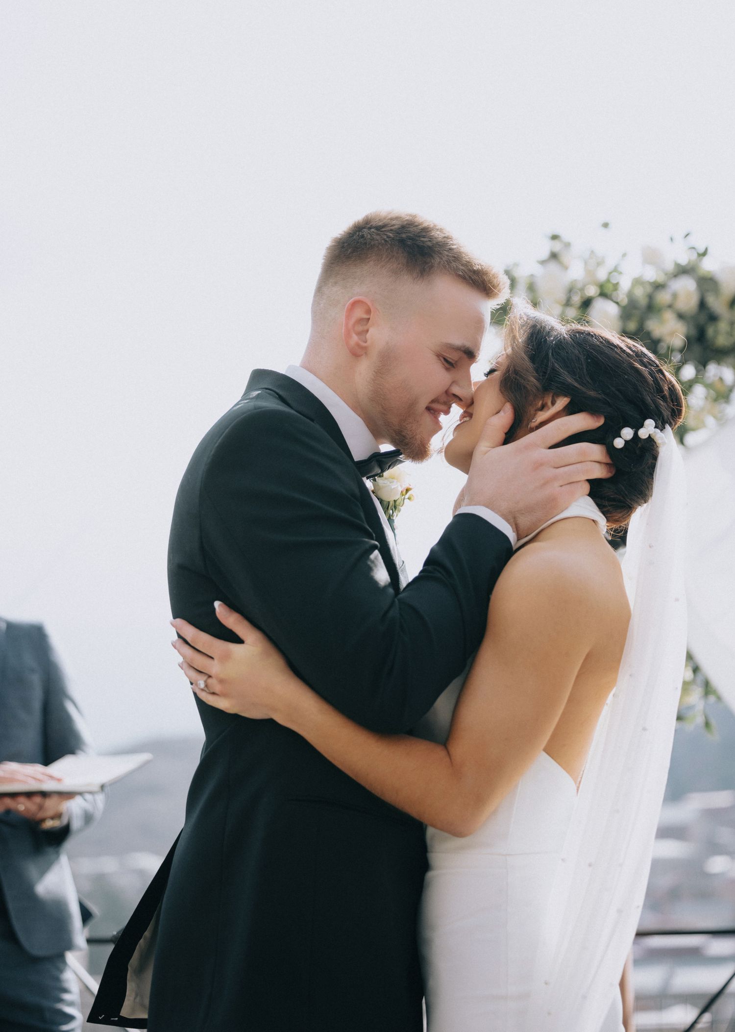 Intimate wedding ceremony moment as couple embraces on scenic overlook with mountains in background.