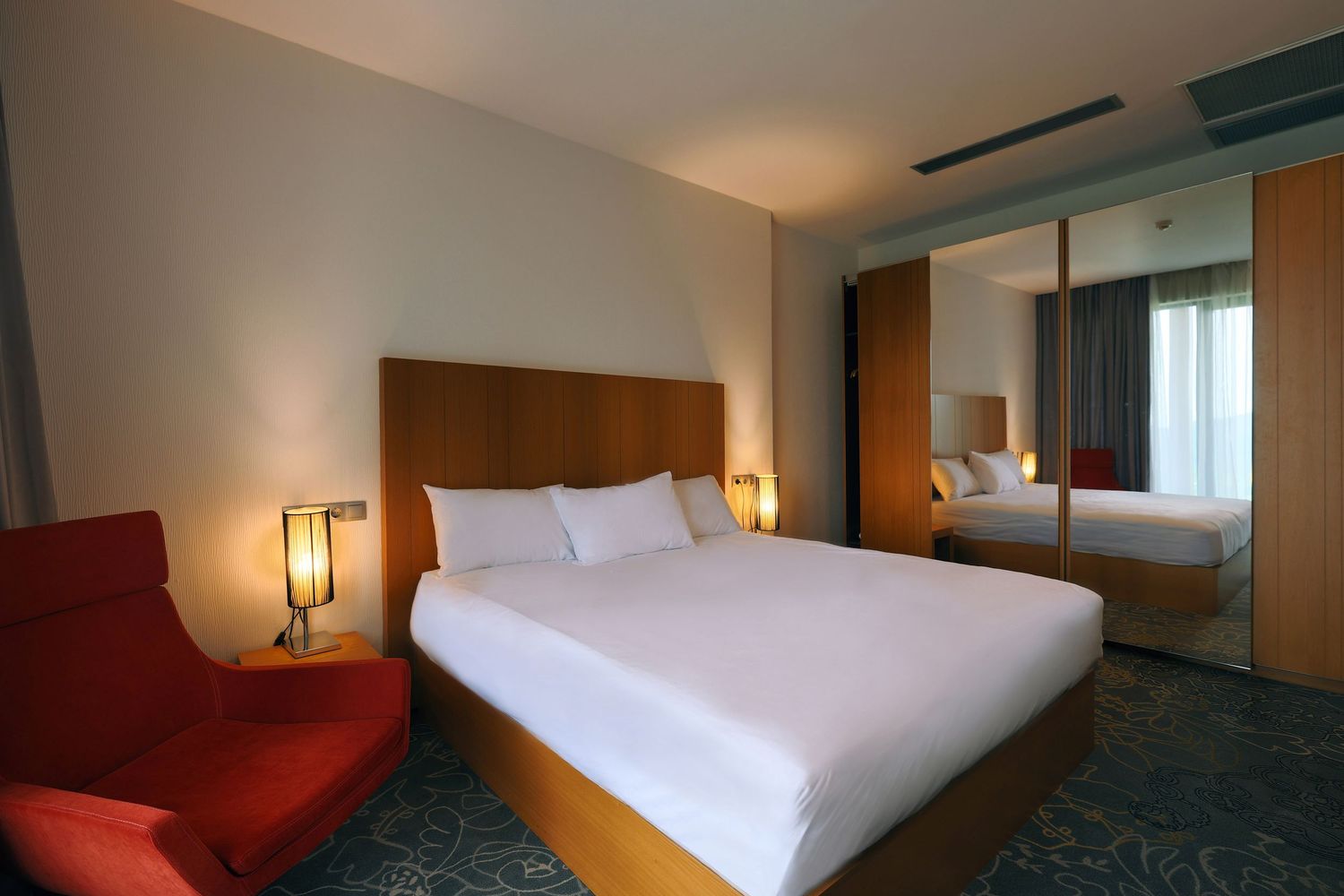 Modern hotel room interior with minimalist furniture and clean white bedding.