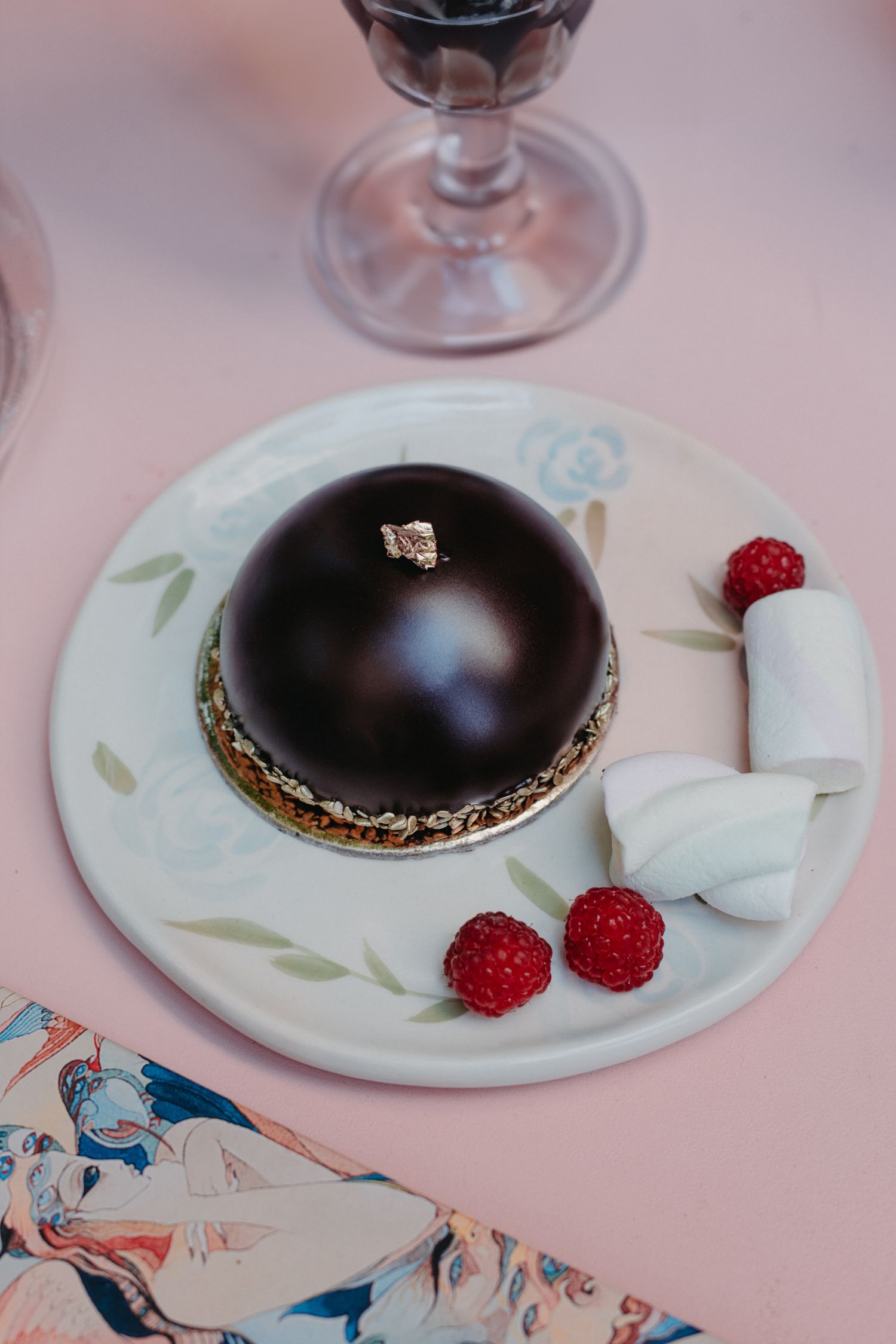 Chocolate dessert with fresh raspberries and marshmallow on a floral patterned plate.