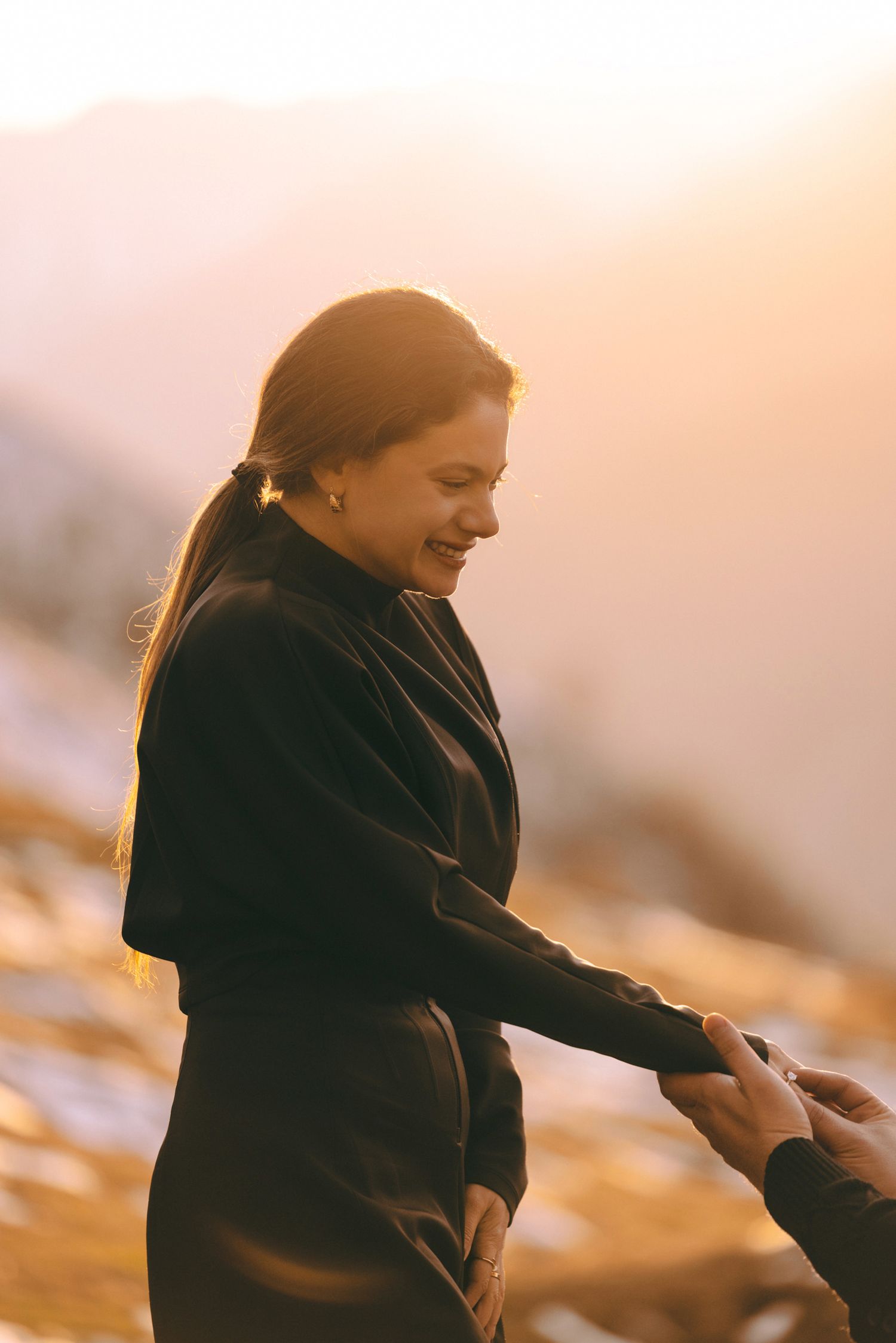Person smiling warmly during a winter sunset in the mountains.