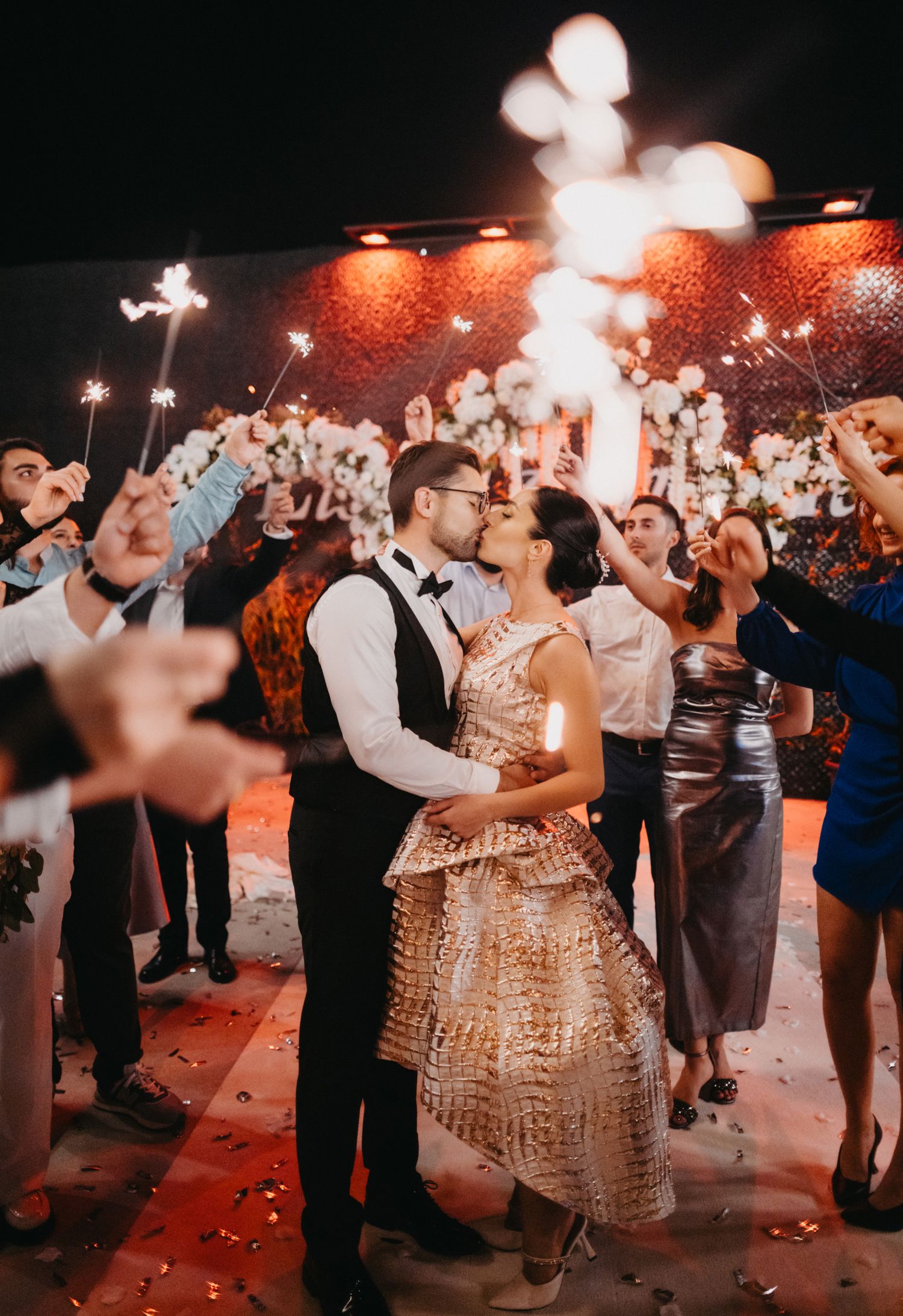 Wedding celebration with sparklers and dancing at an outdoor evening reception.