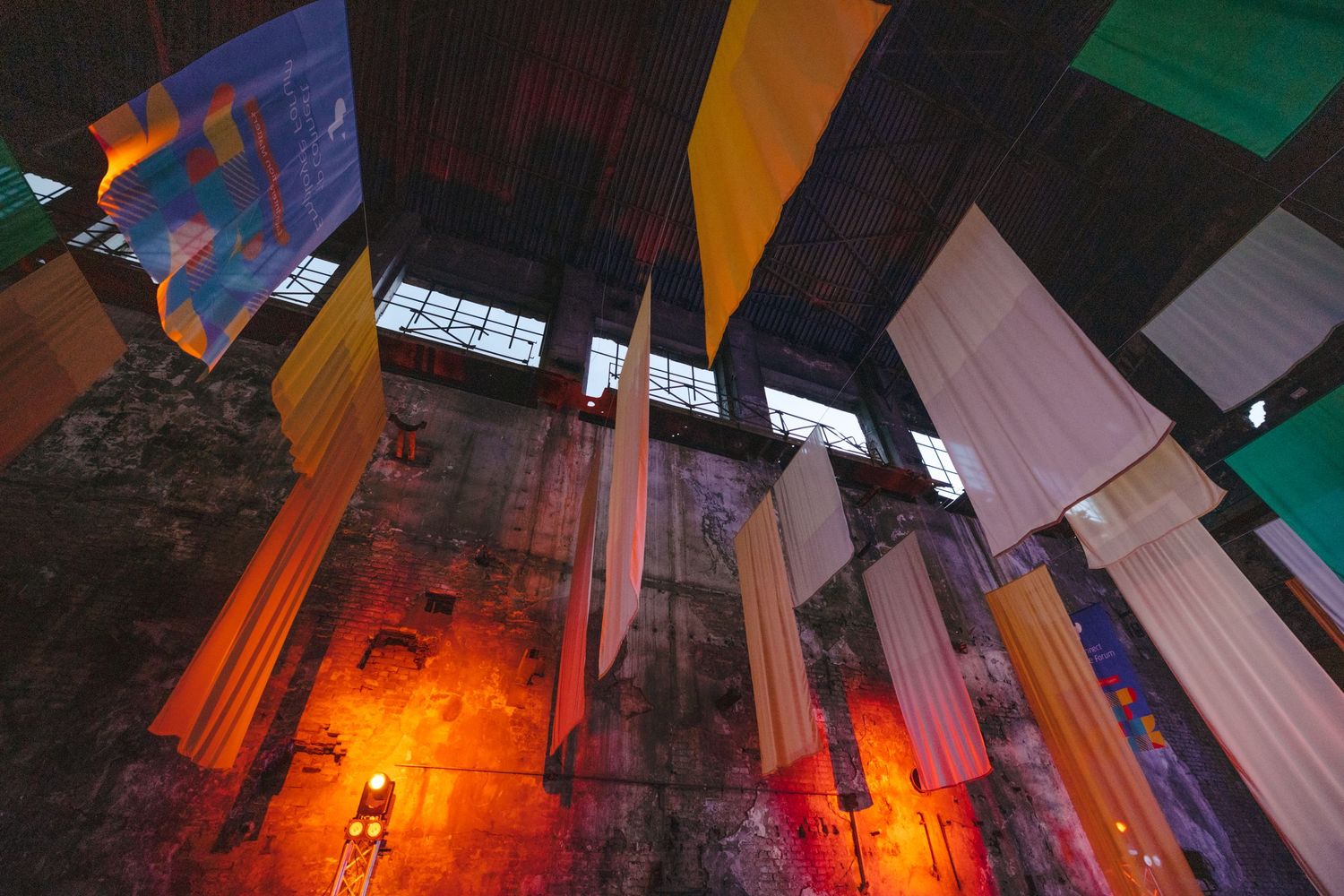 Colorful fabric installations with dramatic lighting in an industrial space.