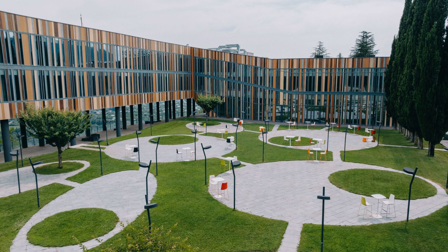 Panoramic view of a modern building complex with curved walkways and circular garden features.