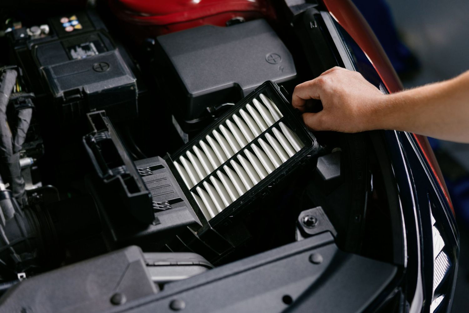 Mechanic replacing a car engine air filter during routine vehicle maintenance service.
