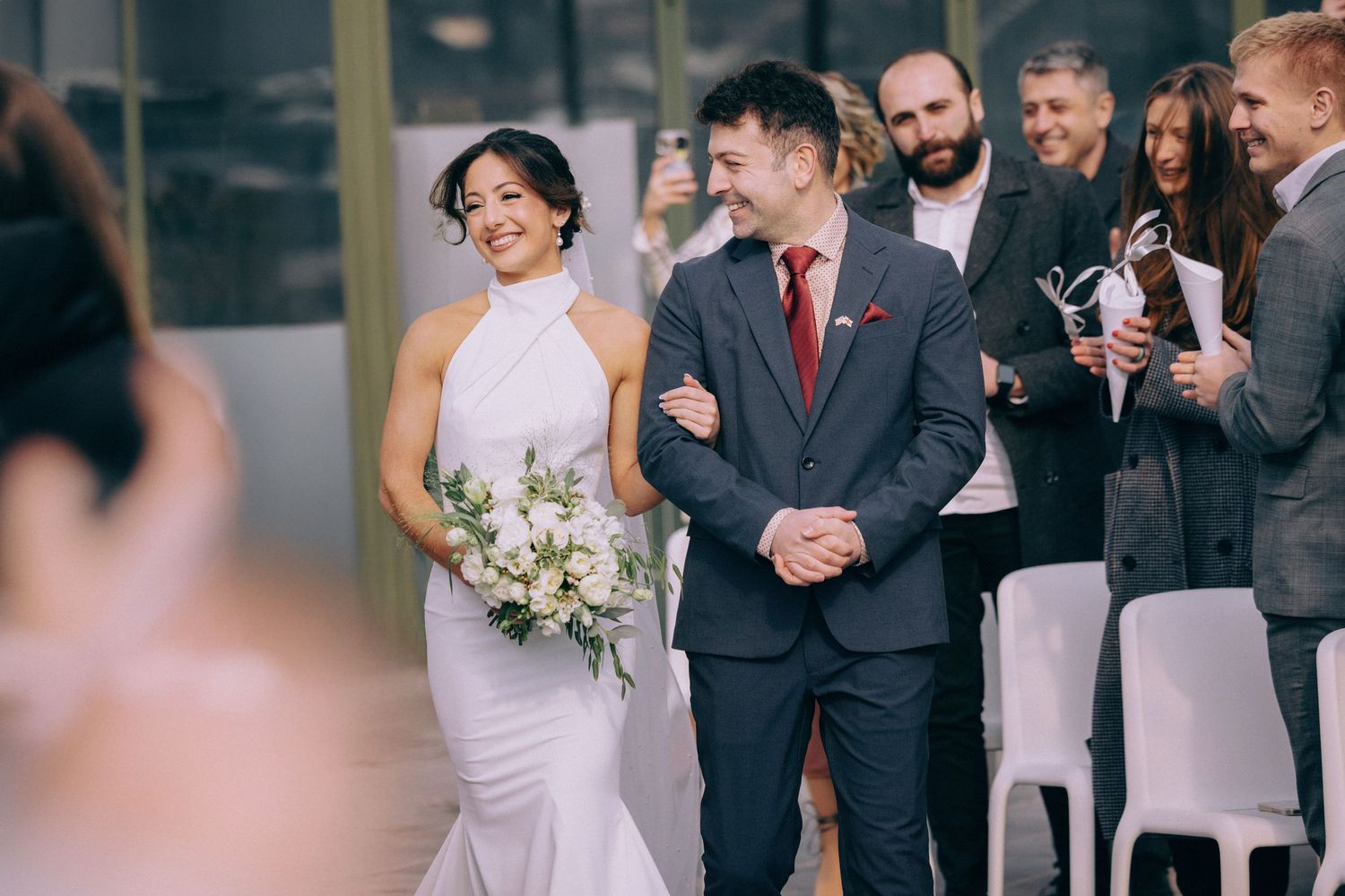 Wedding party stands together outdoors in formal black suits and dresses.