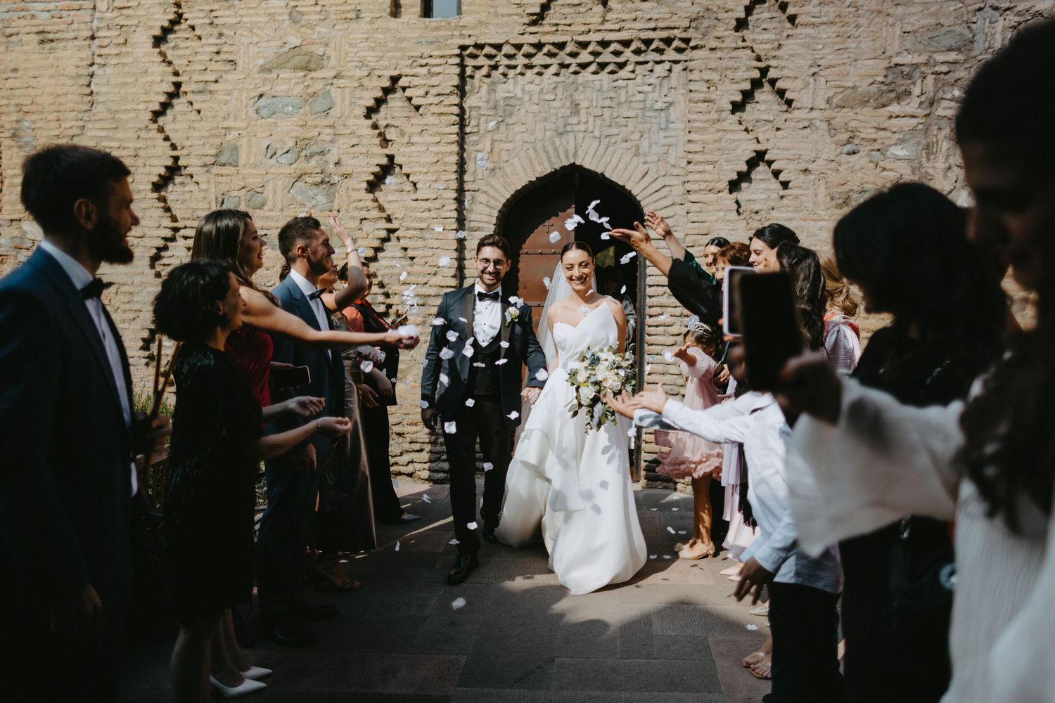 Wedding guests dance and celebrate in rustic brick-walled reception venue.