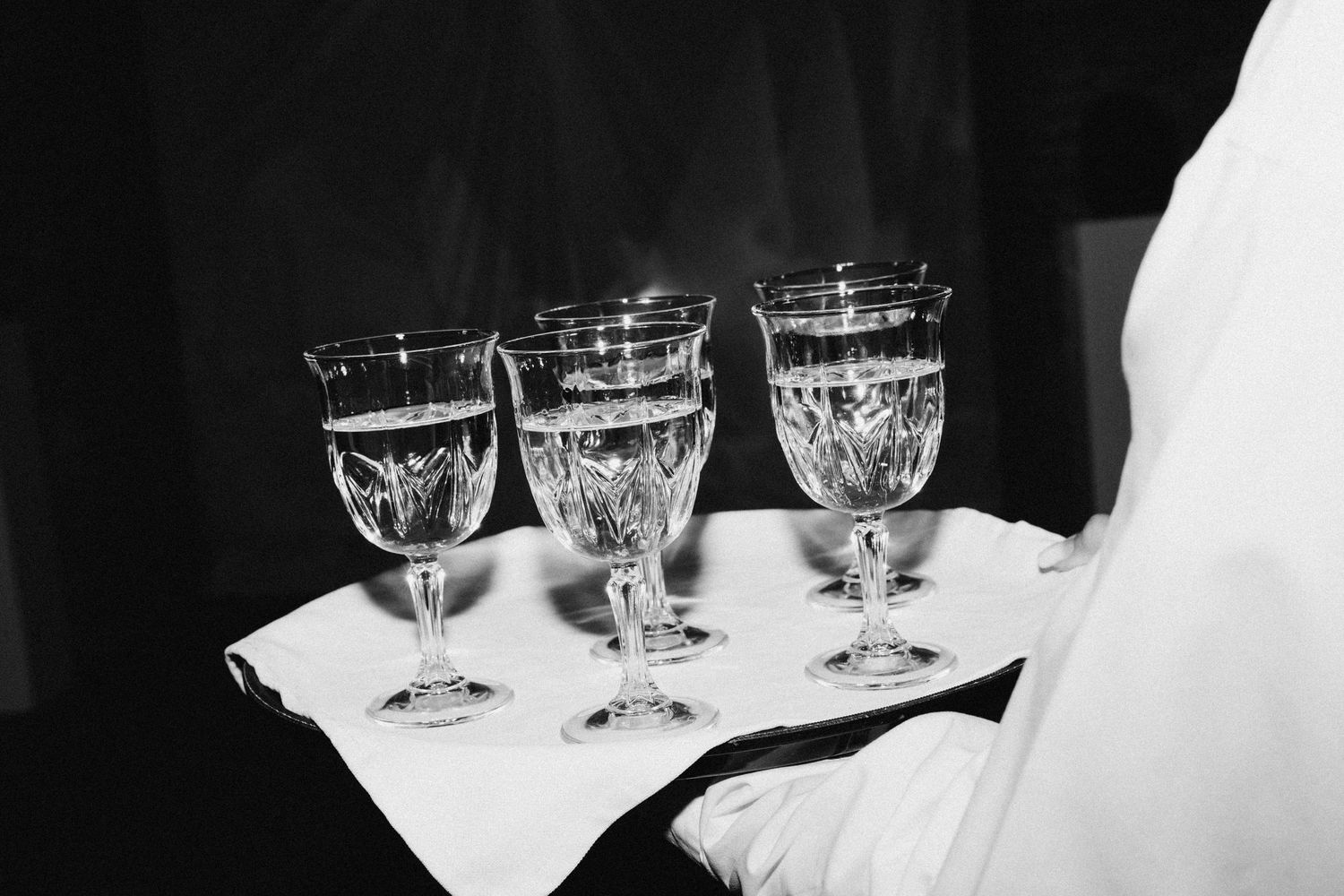 Crystal wine glasses arranged on white serving tray in elegant setting.