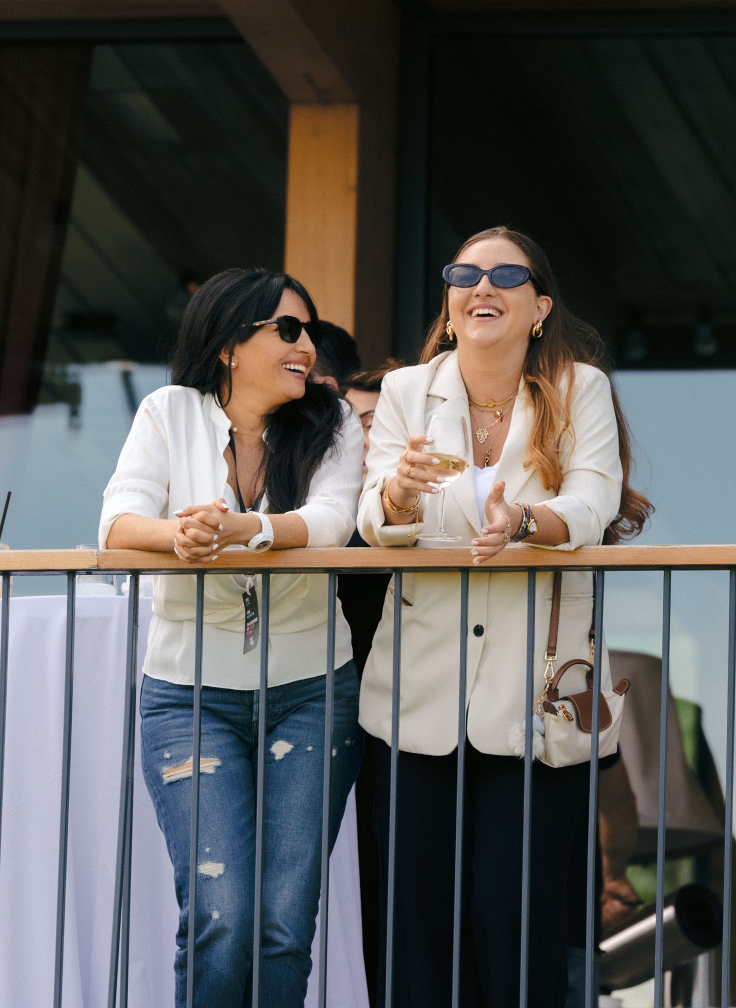 Group of people in white jackets laughing and socializing on a balcony railing.