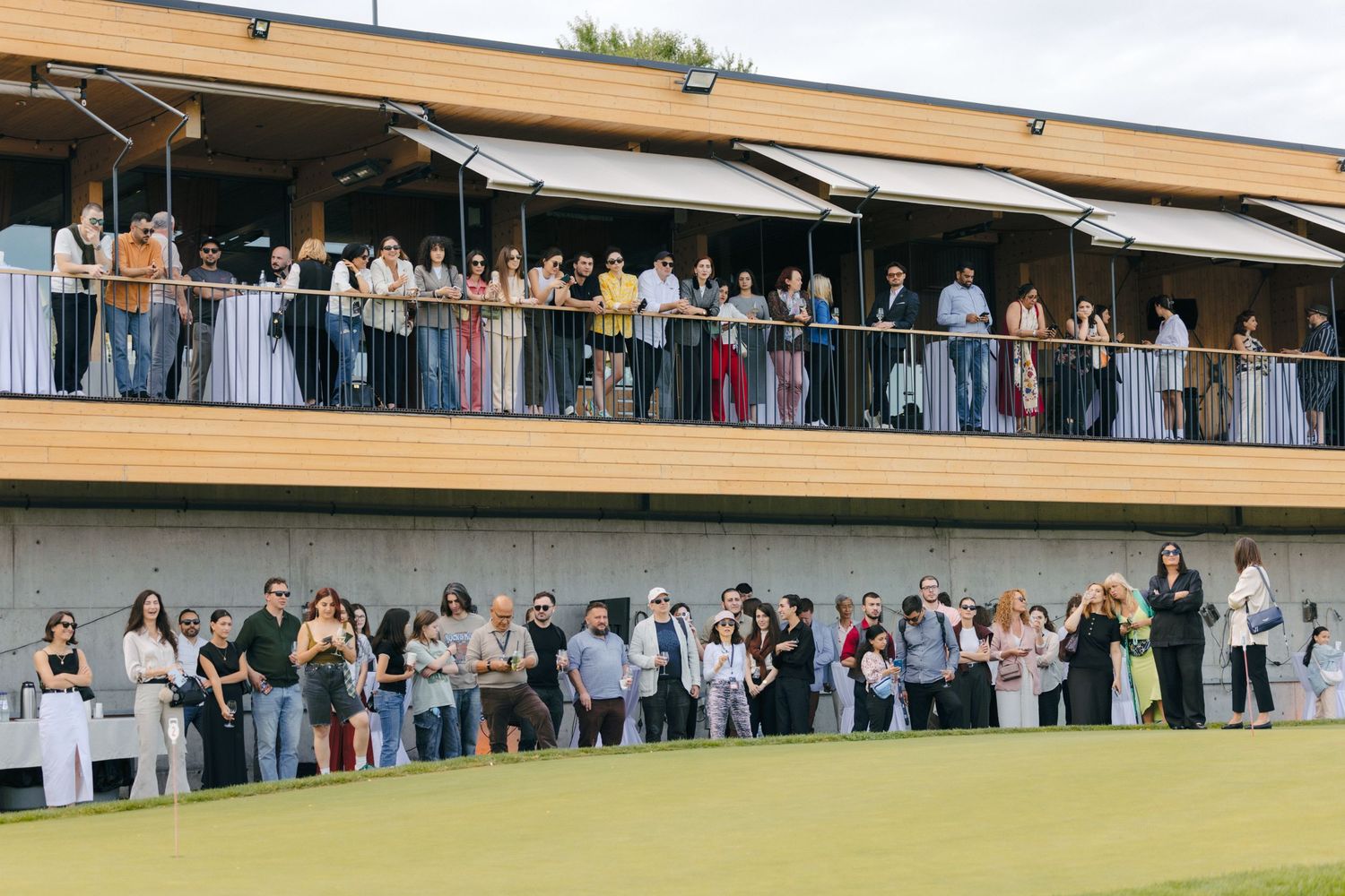 Crowd of people lined up along a covered outdoor viewing area.