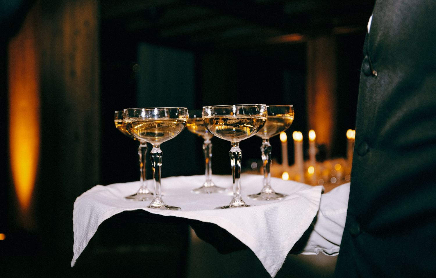 Row of wine glasses arranged on white tablecloths in an upscale dining setting.