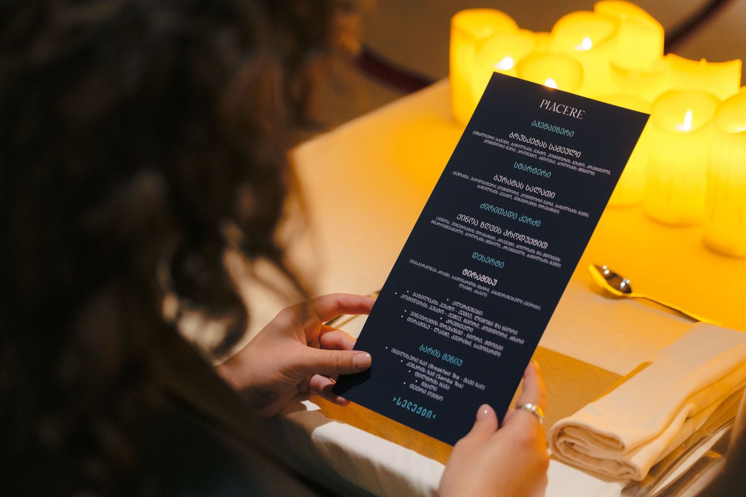 Diners reading elegant black menus in a candlelit restaurant setting.