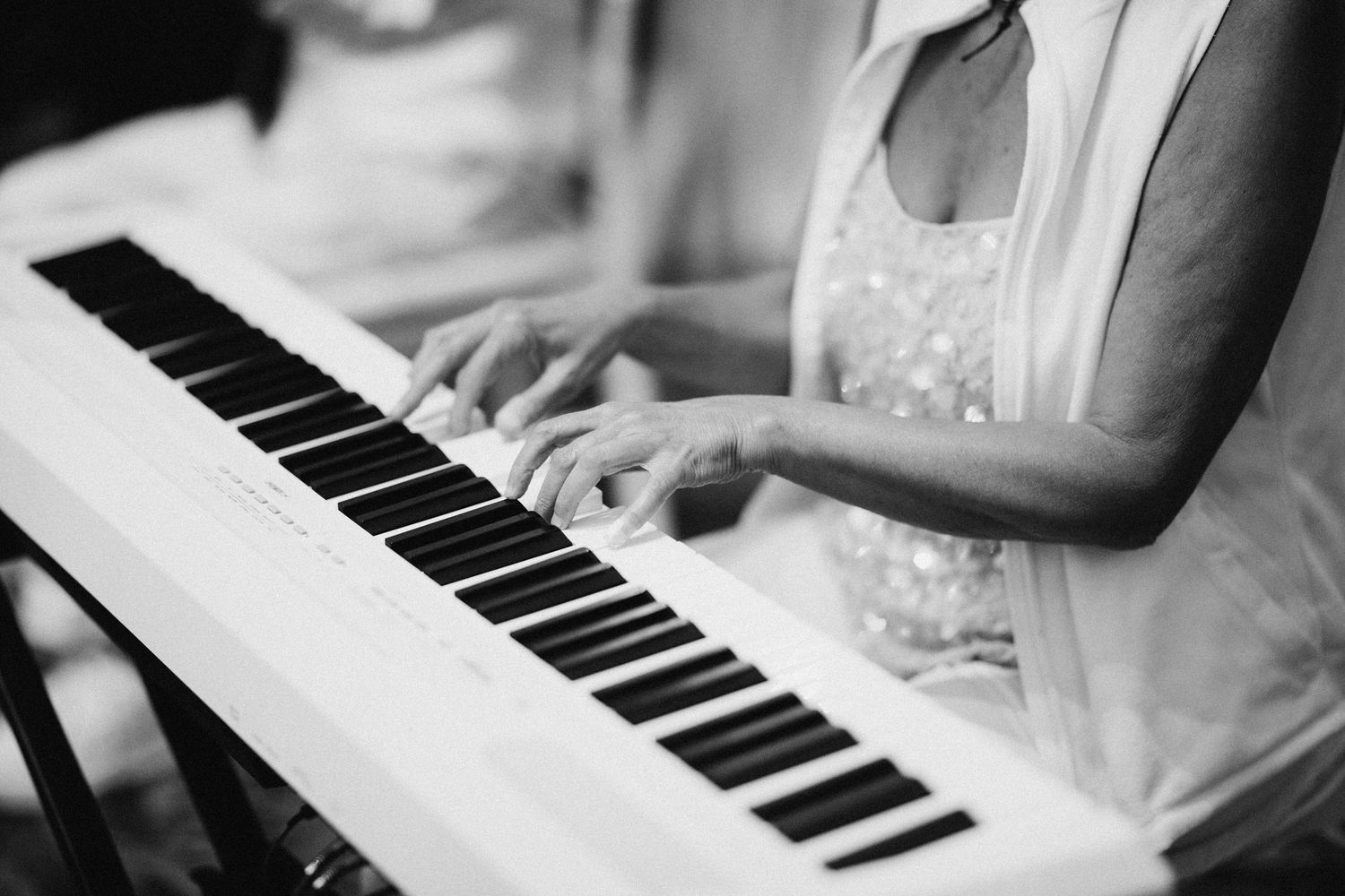 Close-up of hands playing piano keys in black and white.