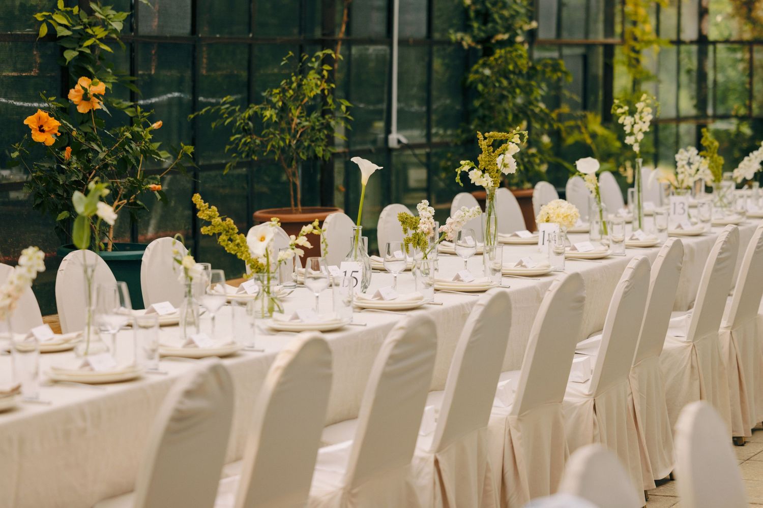 An elegant wedding reception table set with white linens and sunflower decorations.