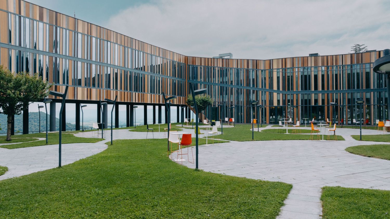 Long horizontal view of contemporary building facade with glass panels and vertical wood elements.