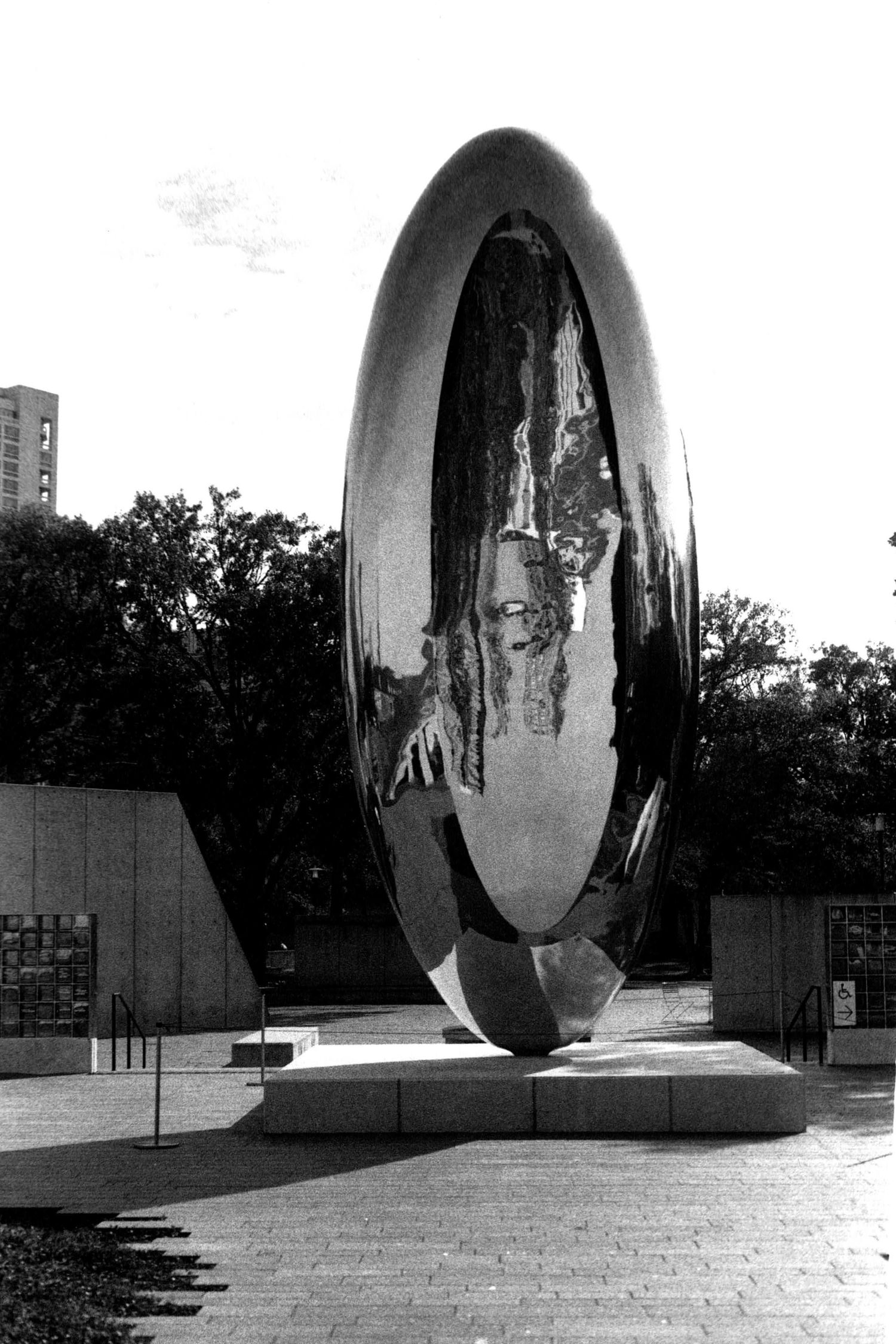 Large reflective metal sculpture by Anish Kapoor creating mirror-like distortions.
