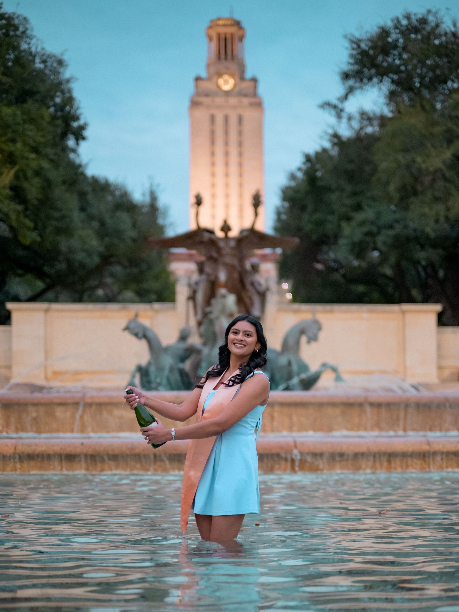 A serene evening photoshoot at the University of Texas Tower with reflections in the Littlefield Fountain.