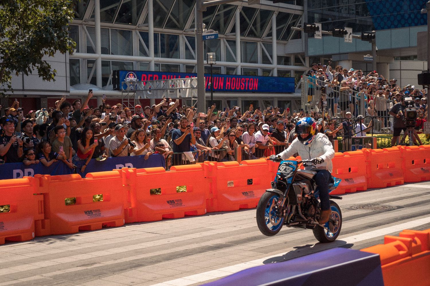 Motorcycle racing event with orange barriers and purple track markings on a city street.