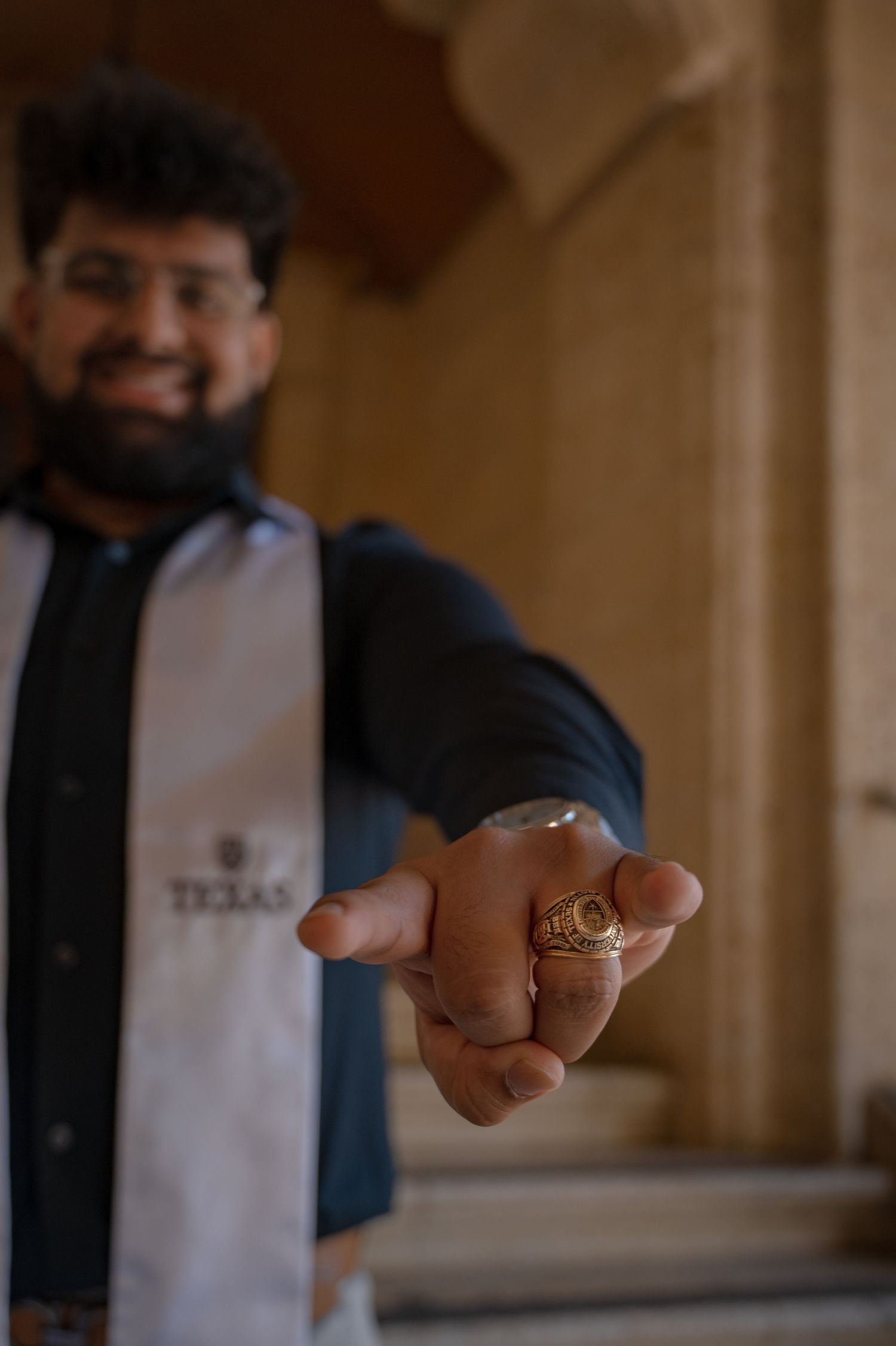 Close-up shot of class ring being displayed against blurred campus background.