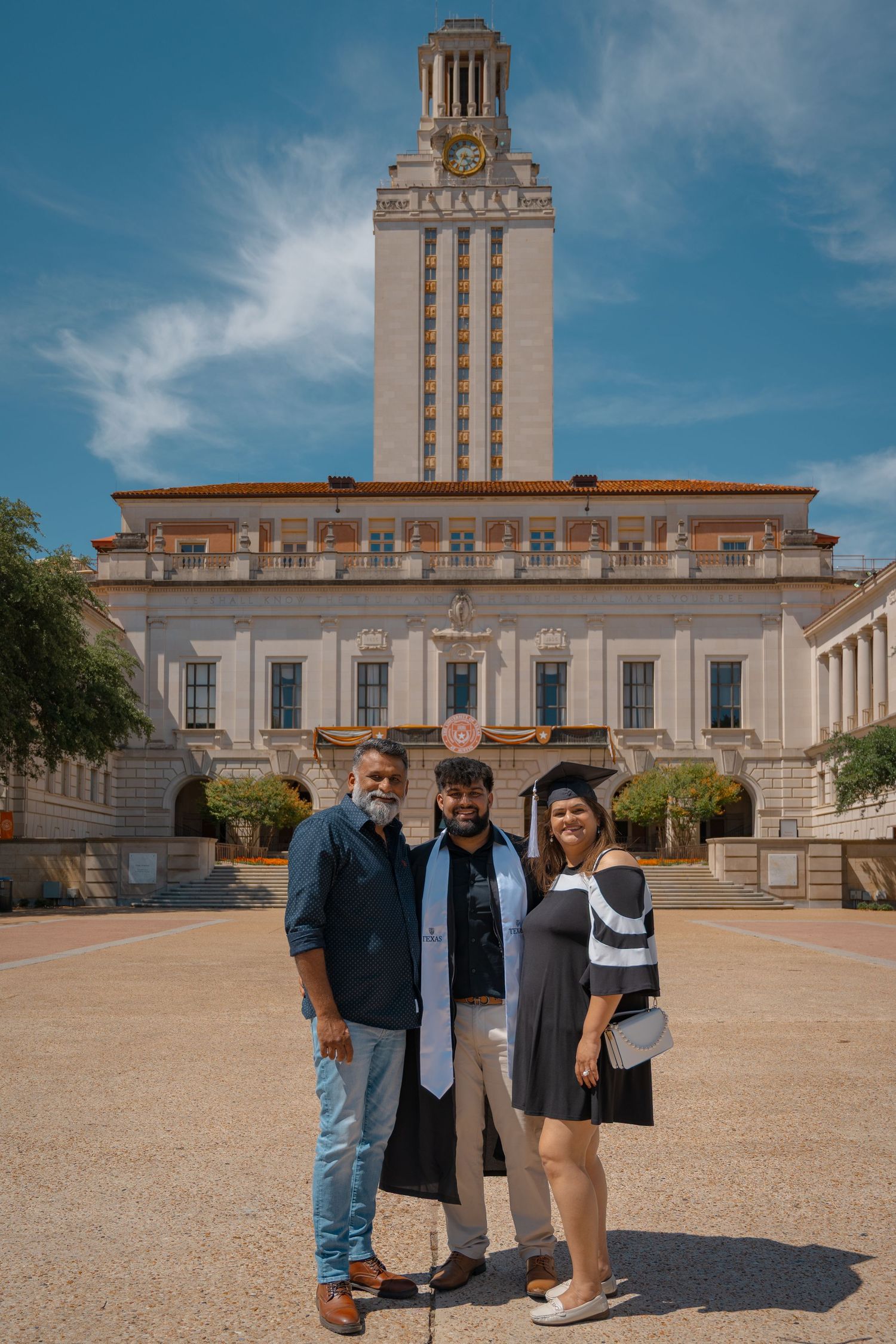 Group graduation photo taken on the main plaza with UT Tower in background.