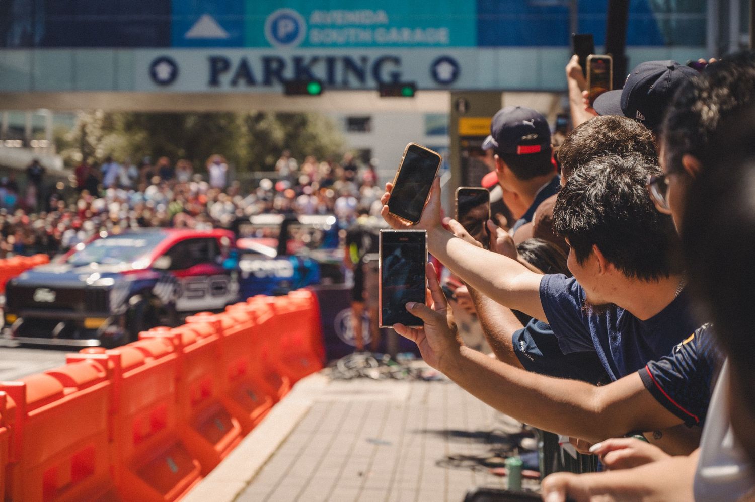 Excited crowd taking photos and videos at an outdoor event.