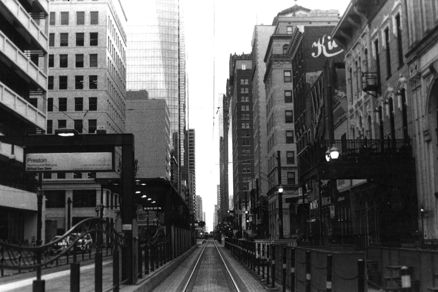 Urban street scene with tall buildings and vintage signs in black and white photography.