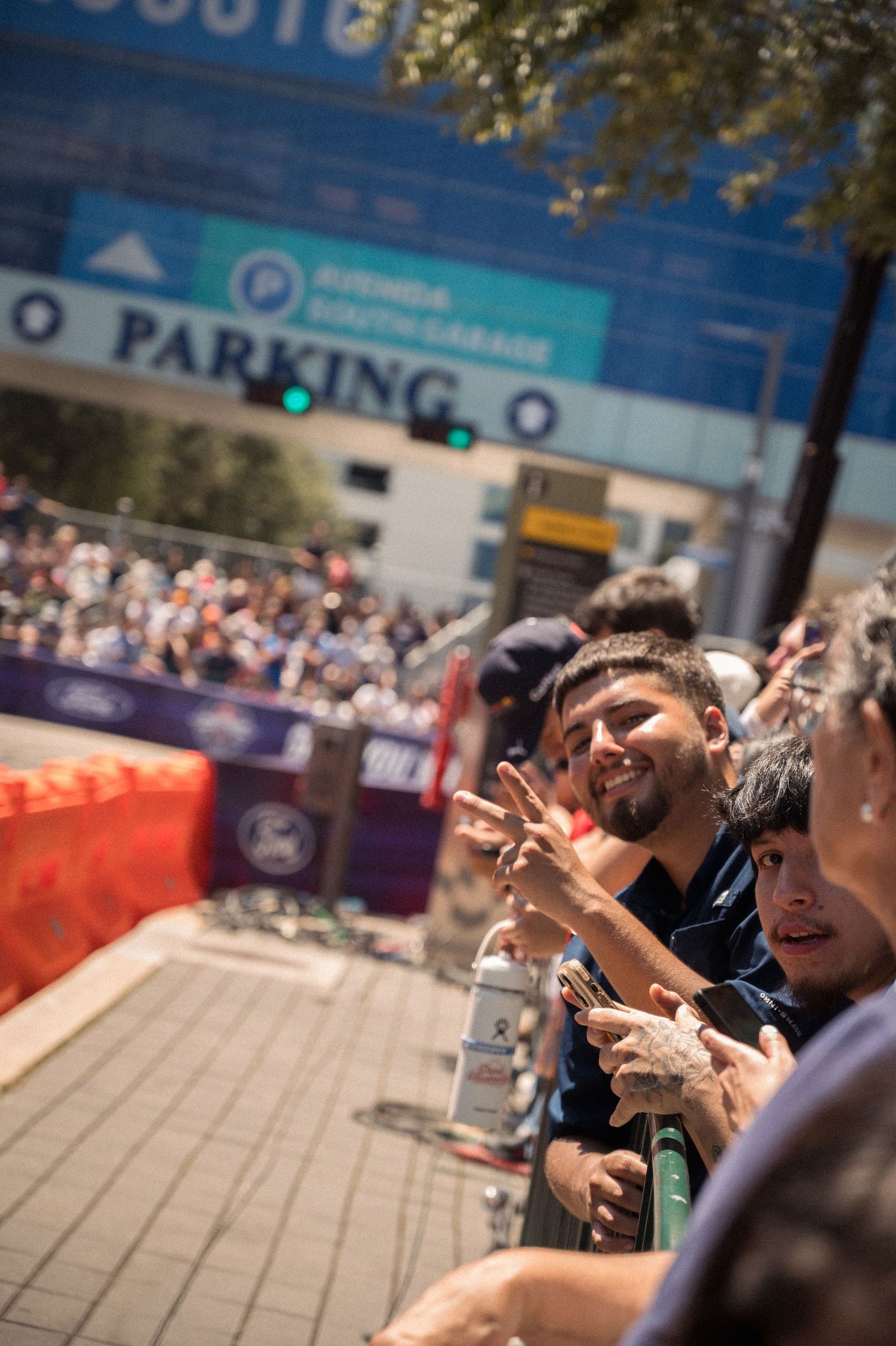 Enthusiastic spectators recording event on smartphones against blue building backdrop.