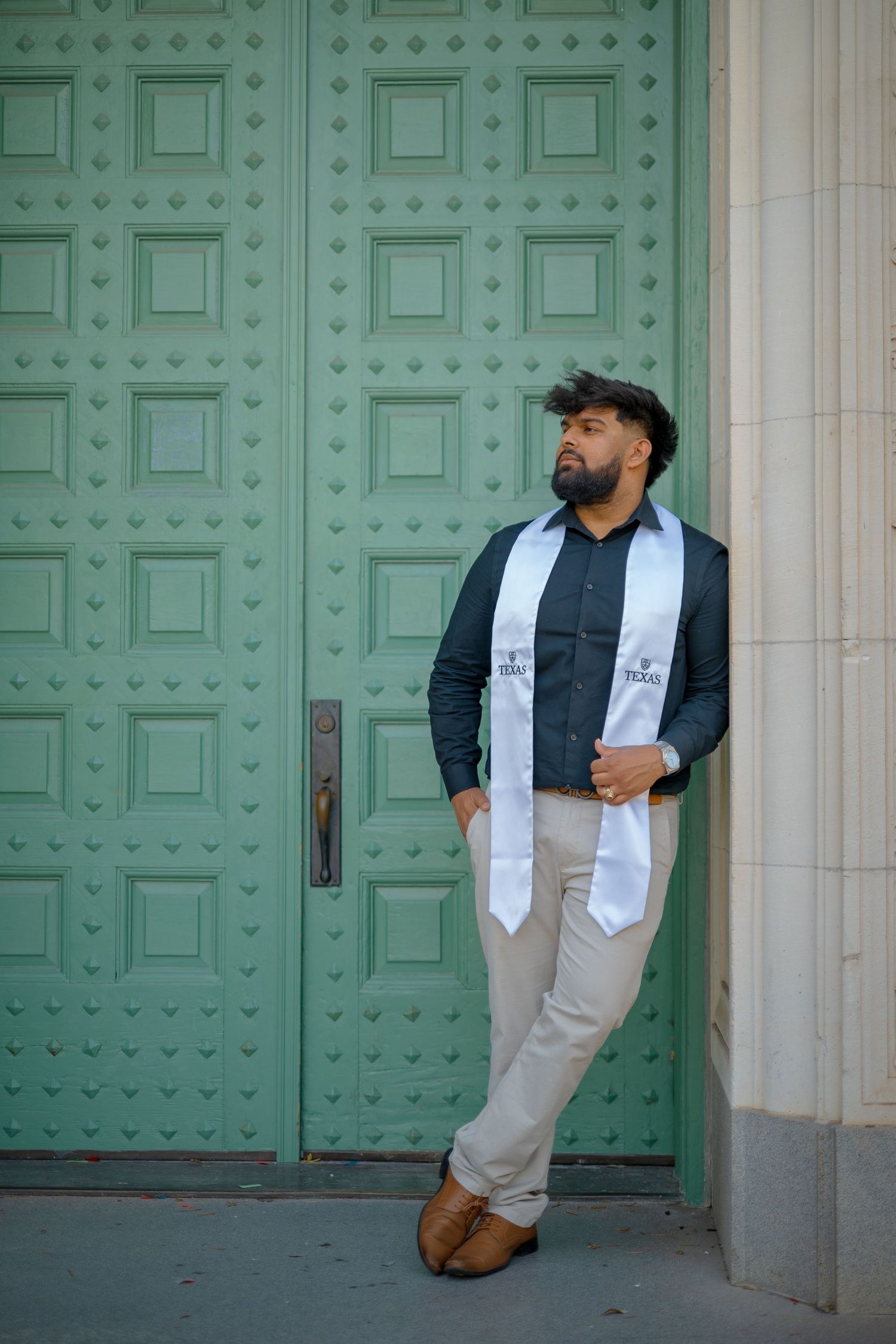 Casual graduation poses against historic mint green doors at UT Austin.